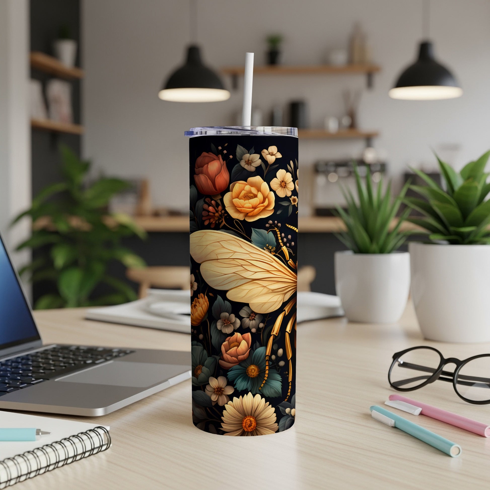 Tall tumbler with bee and floral design, on a desk.