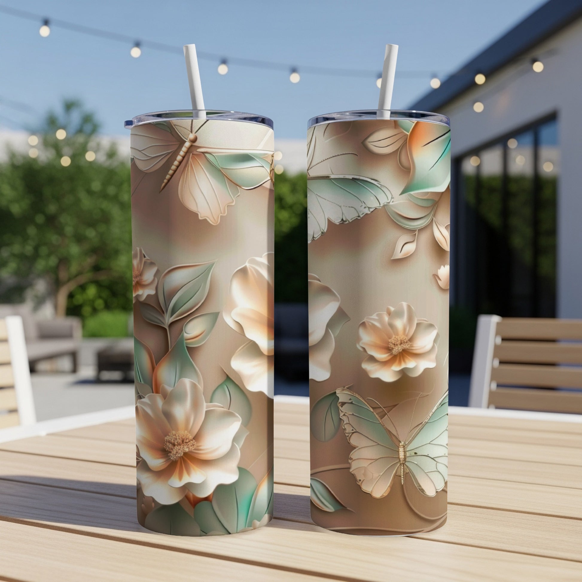 Two tall tumblers with a butterfly and floral design on a table.