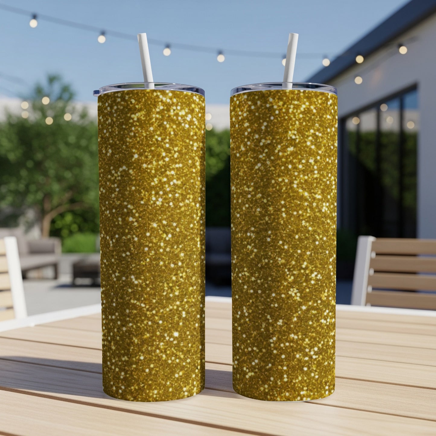 Two gold glitter tumblers with straws on a wooden table.