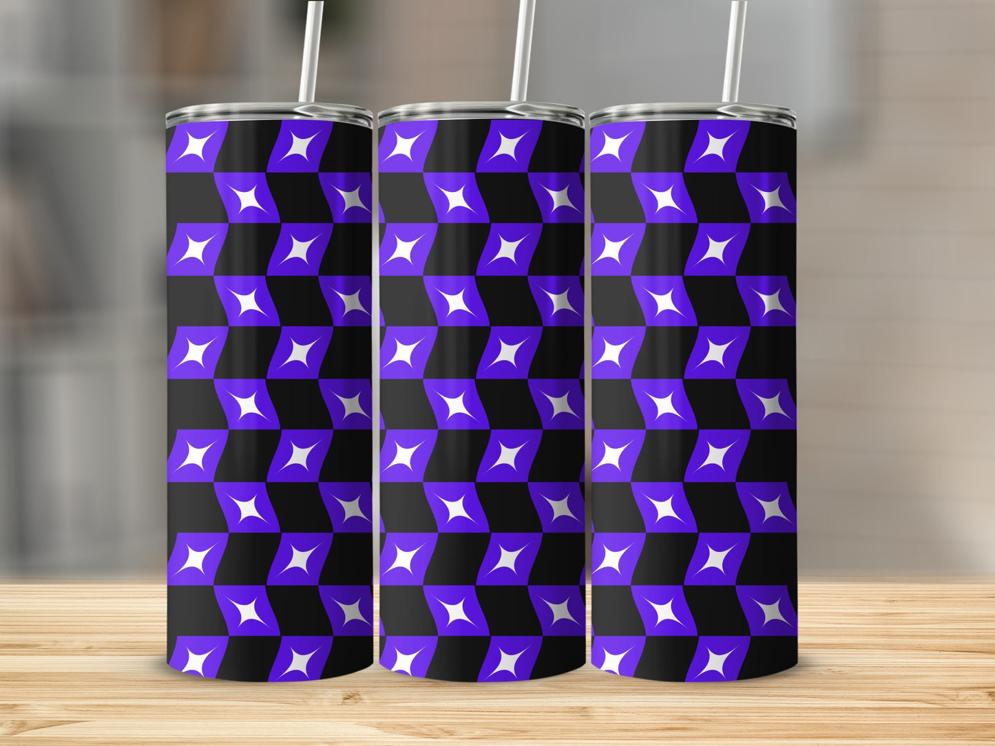 Three purple and white geometric patterned tumblers with straws on a wooden surface.