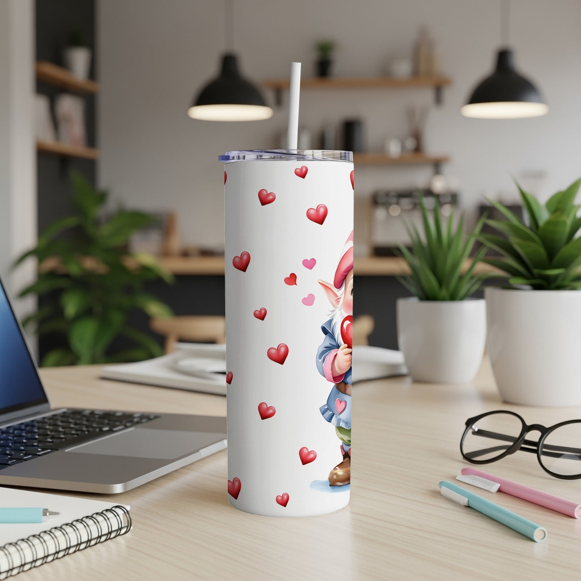 White tumbler with gnome and red hearts design, on a desk.