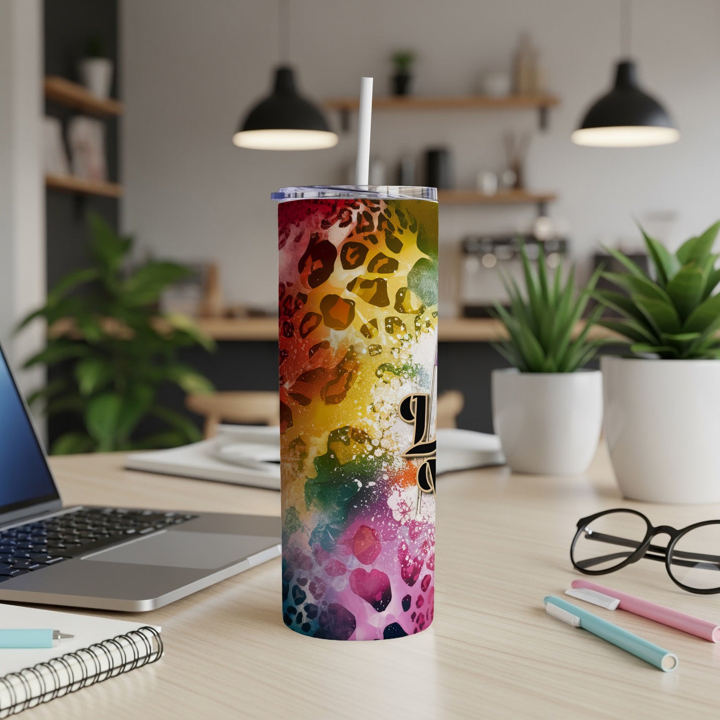 Rainbow leopard print tumbler with straw on a desk.