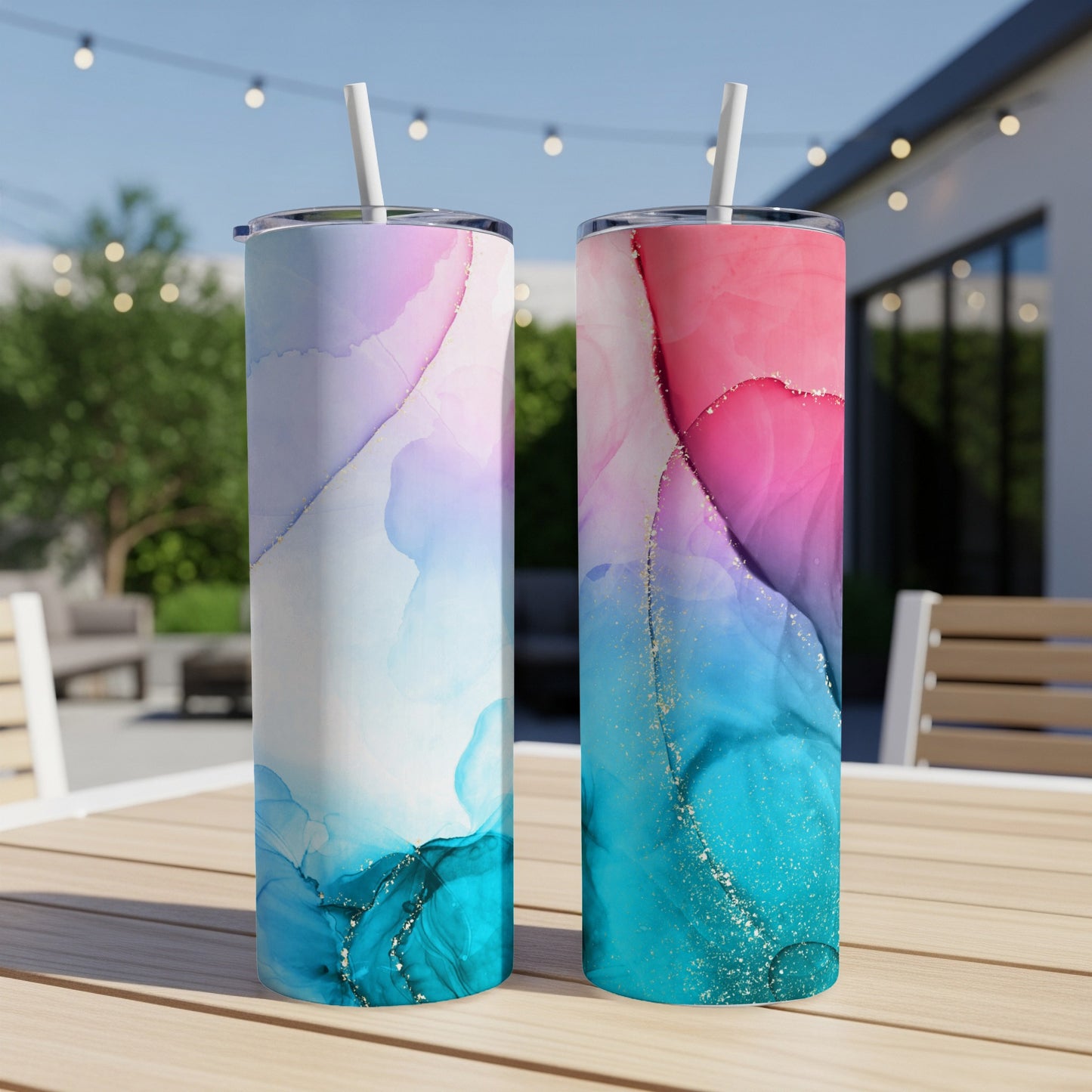 Two tall tumblers with swirling pink, blue, and teal abstract designs on a wooden table.