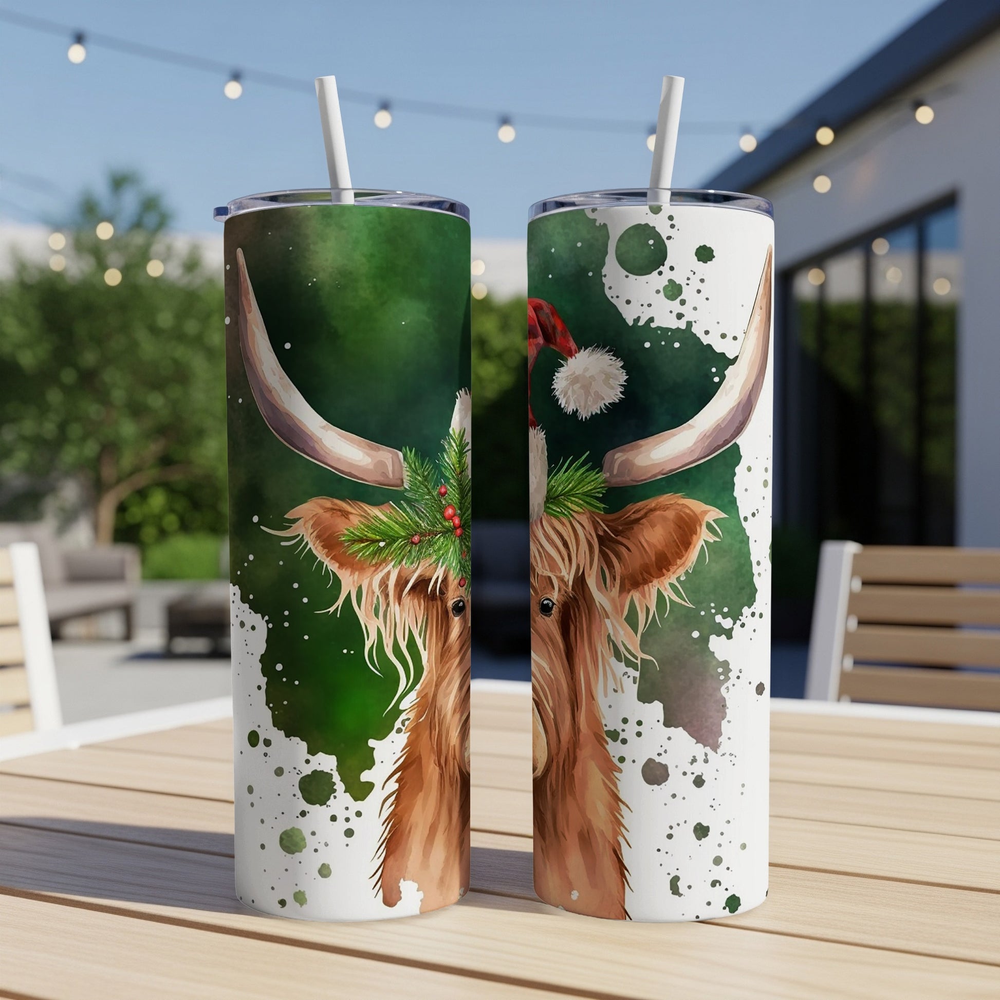Two festive Highland cows with Christmas hats and greenery on tumblers.