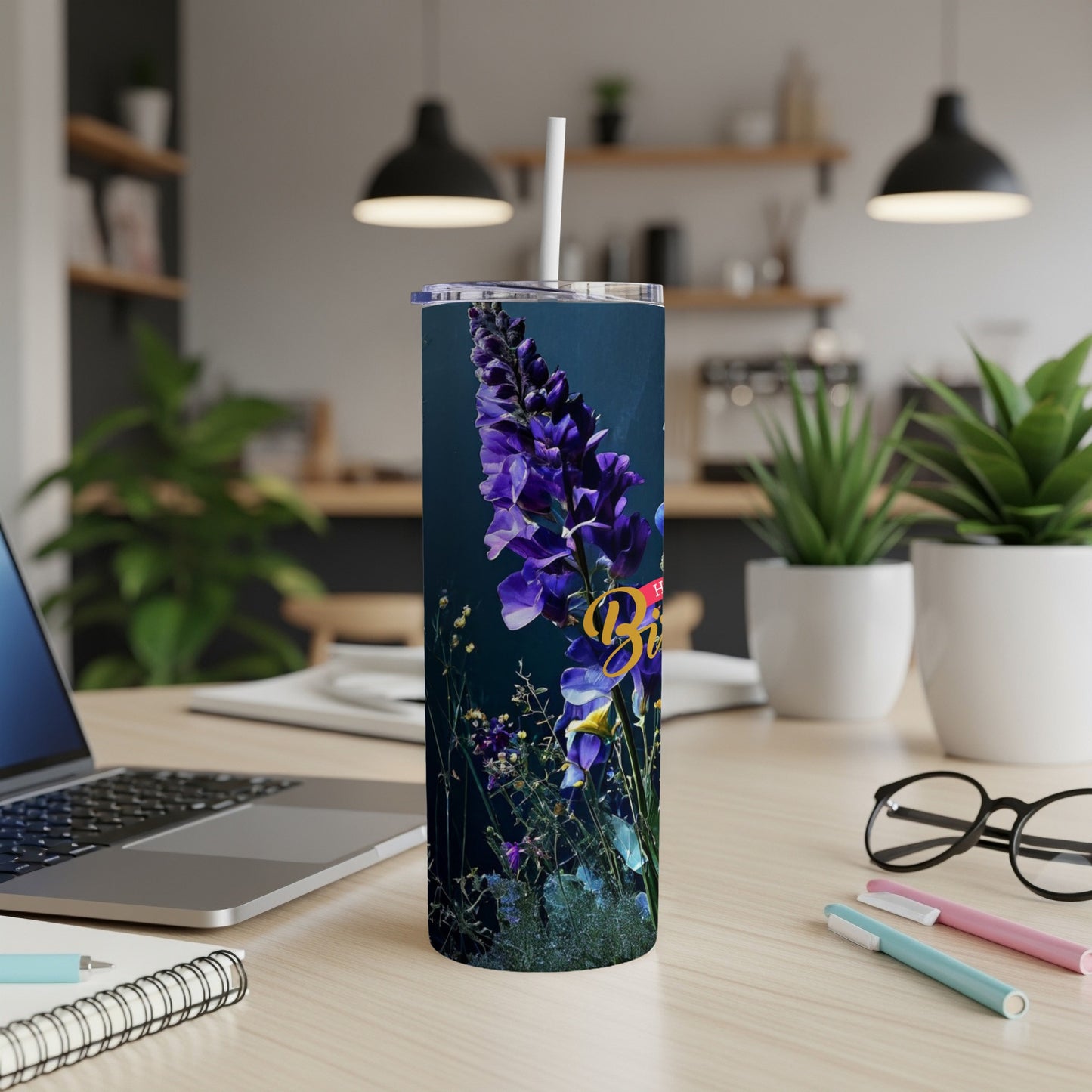 Dark tumbler with purple flowers and text, straw inserted.