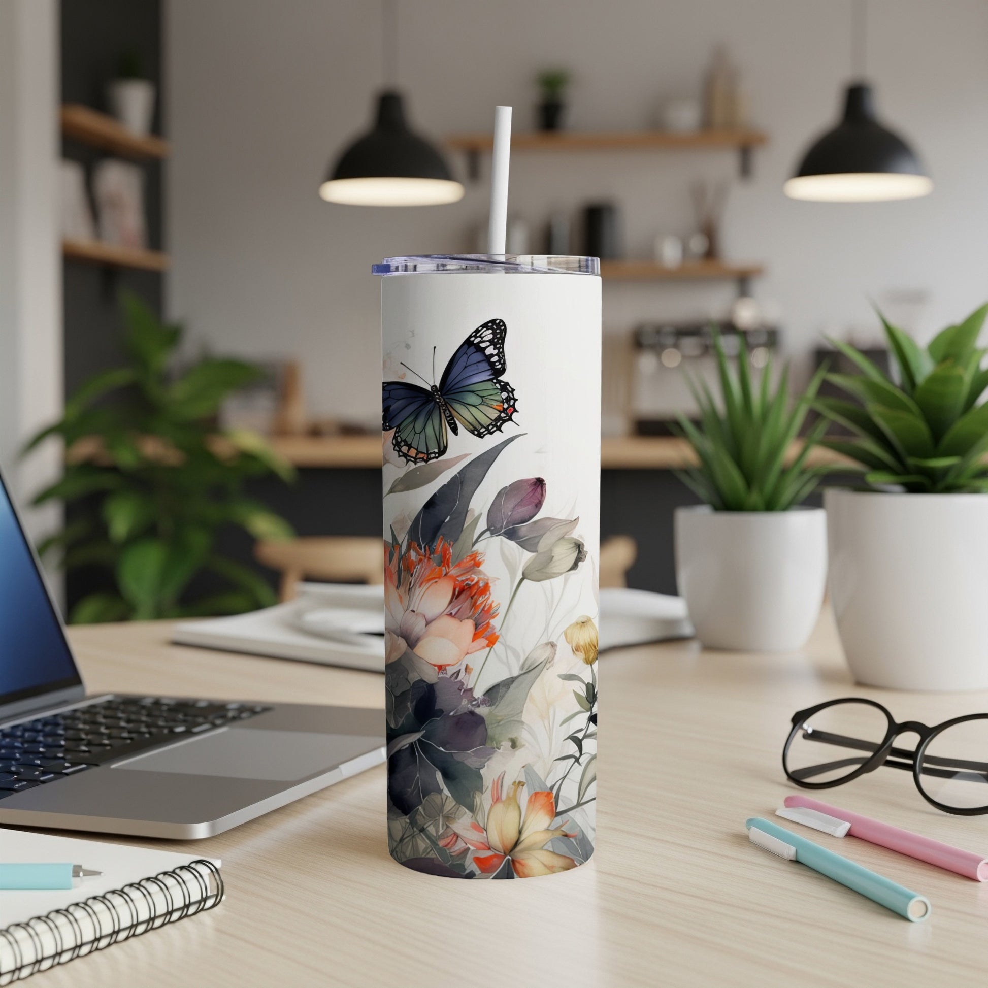 White tumbler with floral and butterfly design on a desk.