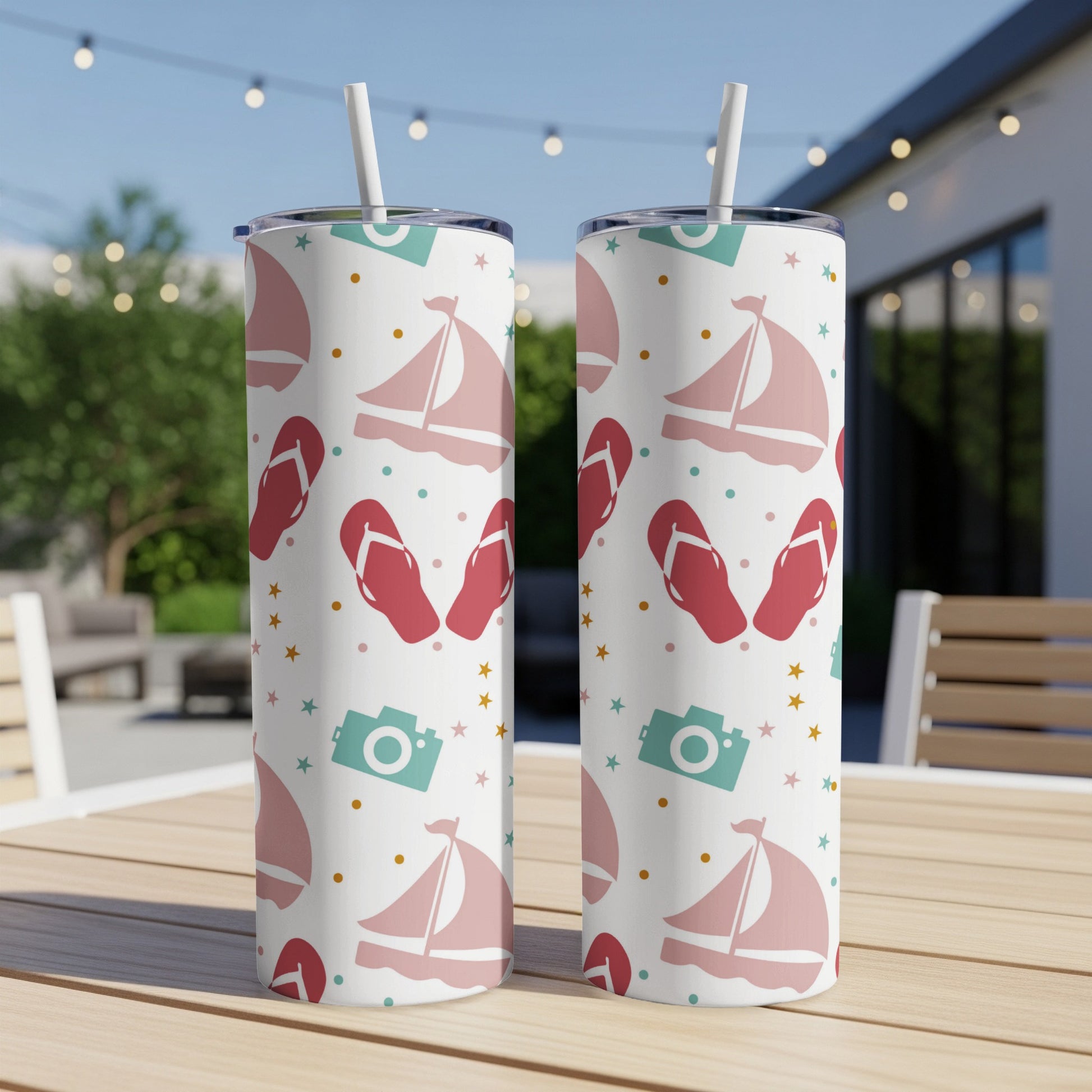 Two pink and white sailboats, flip-flops, and cameras on a white tumbler.