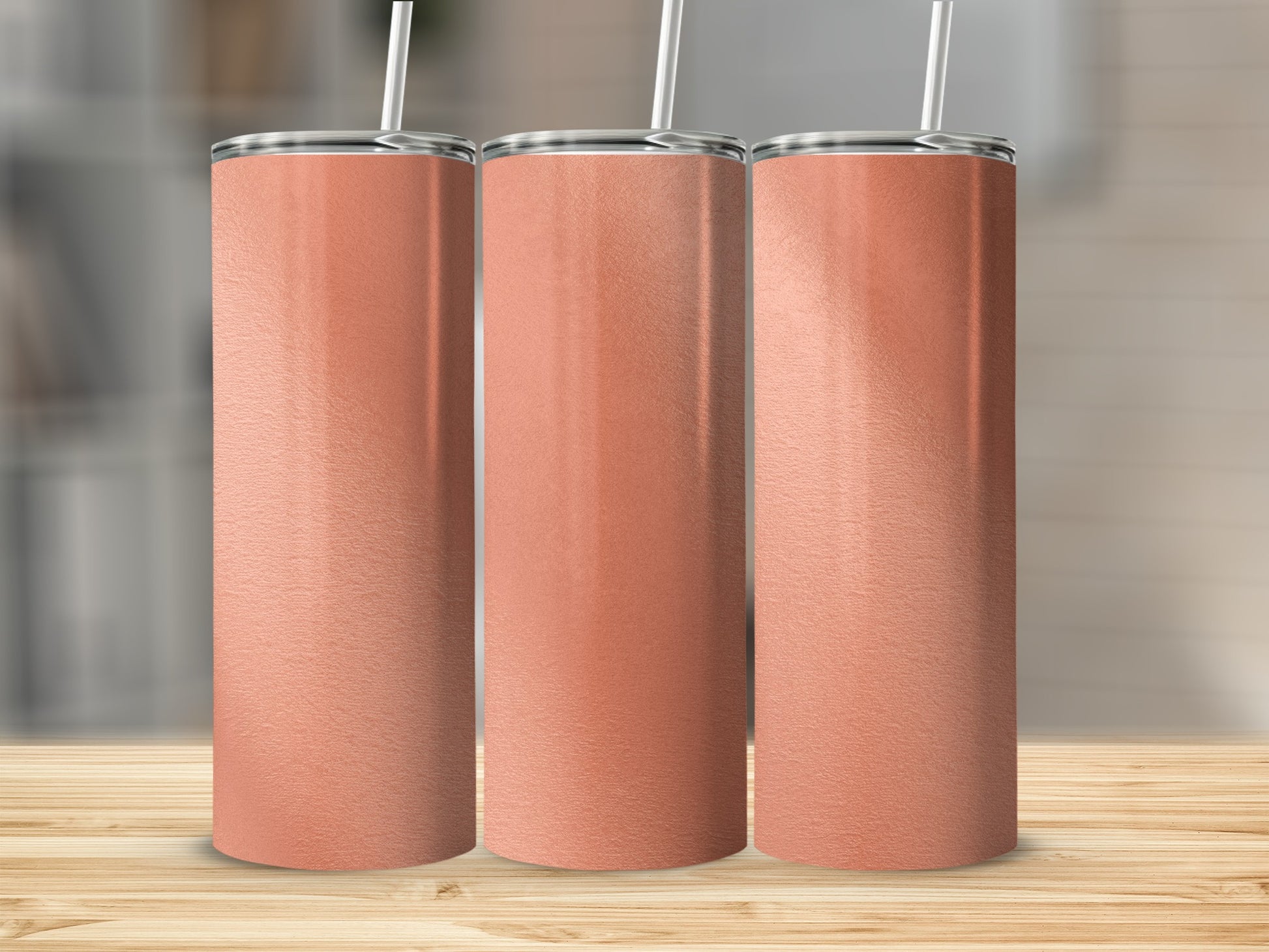 Three blank coral gradient tumblers with straws stand on a wooden surface.