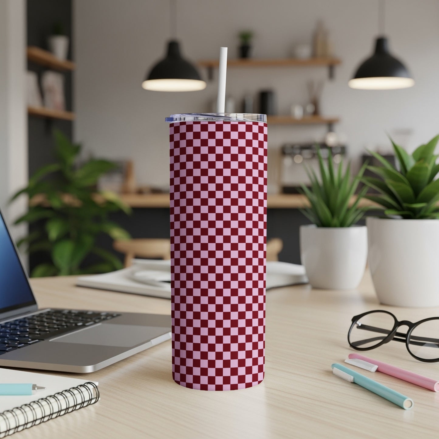 Maroon and pink checkered tumbler with white straw on desk.