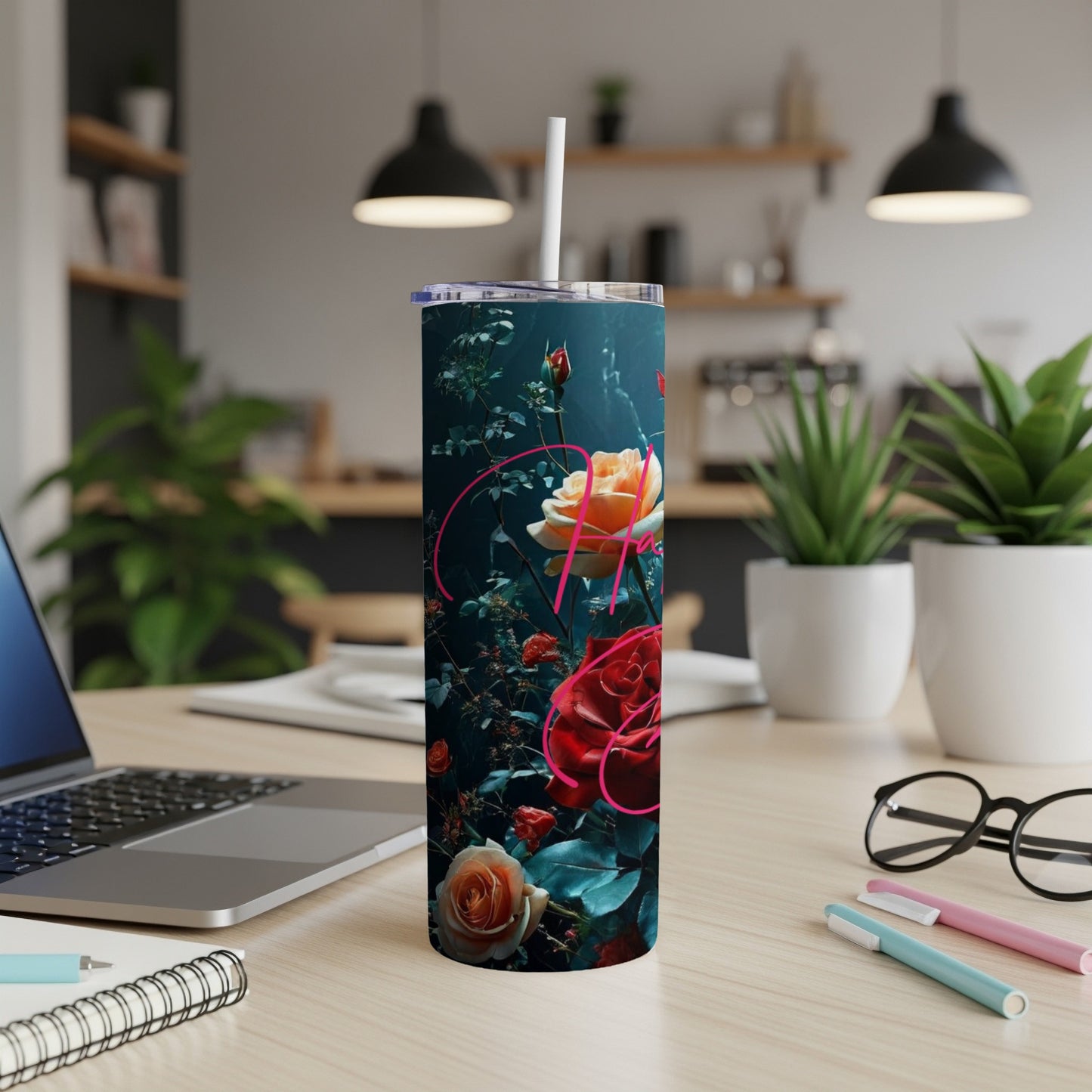 Dark tumbler with roses and script text on a desk.