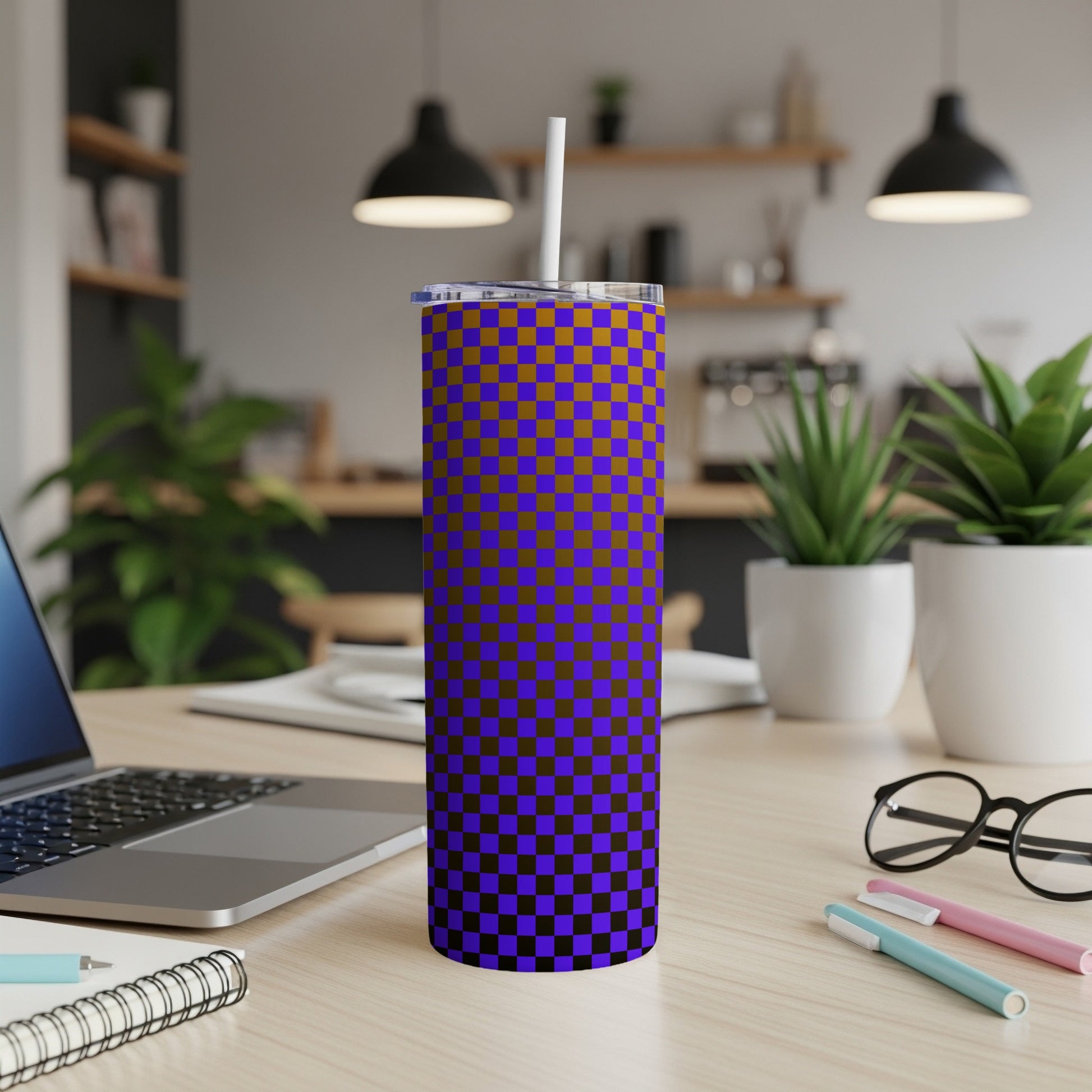Purple and brown checkered skinny tumbler with straw on desk.
