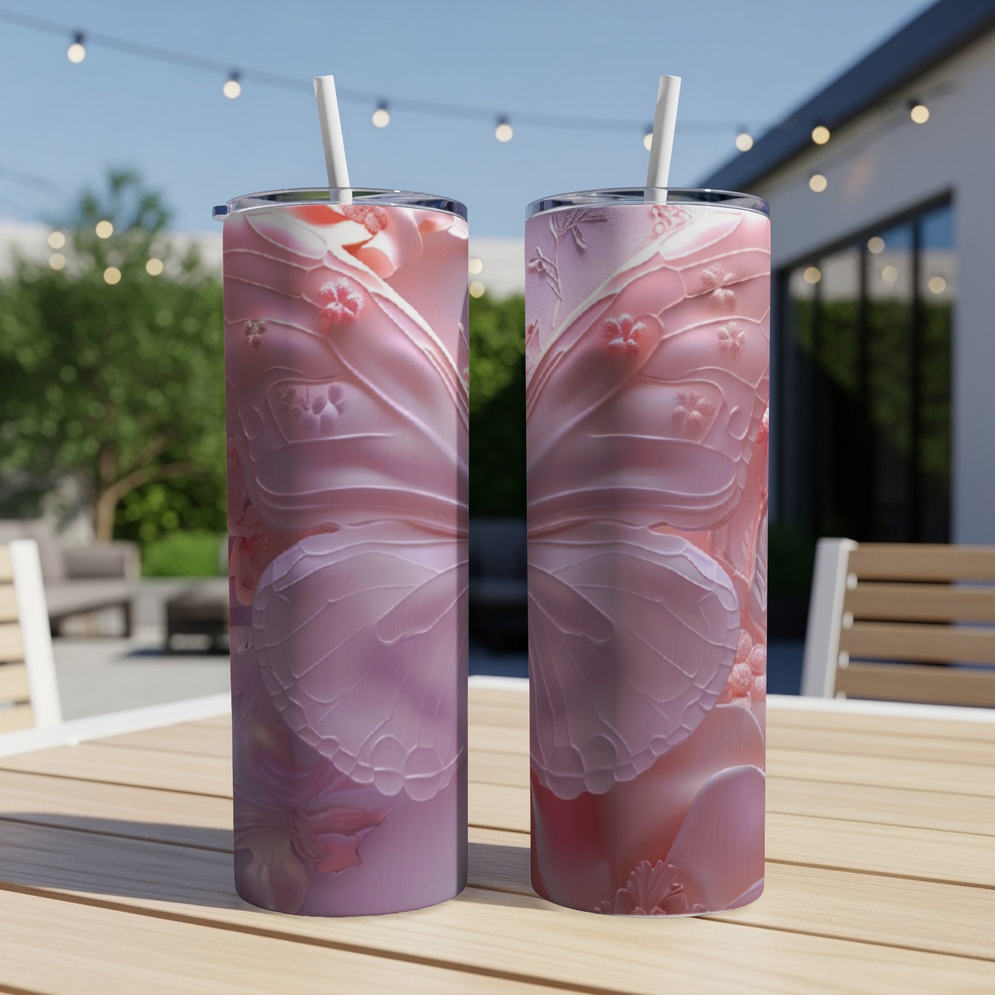 Two pink iridescent tumblers with butterfly wing patterns and straws.