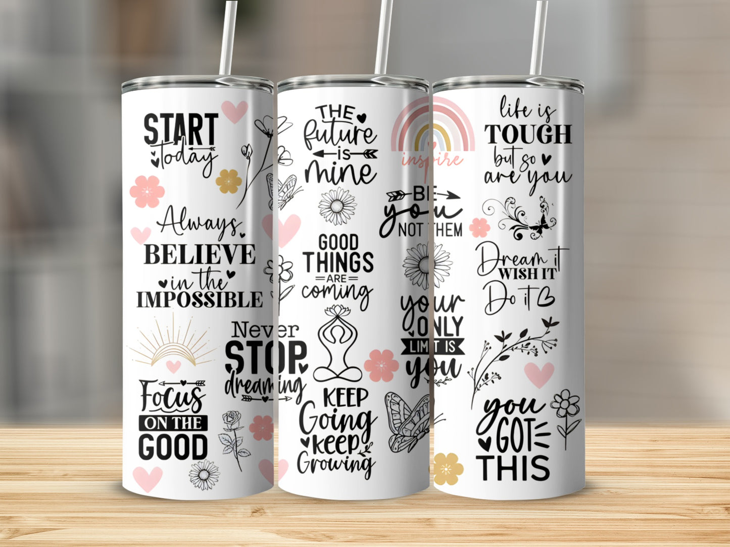 Three tumblers with inspirational quotes and floral designs on a wooden surface.