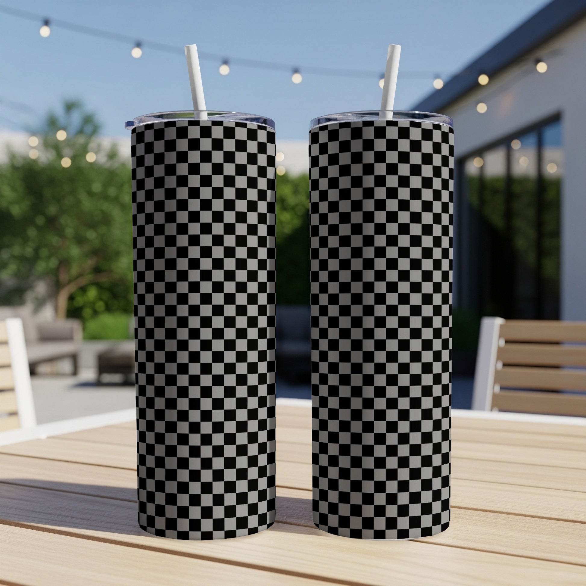 Two tall tumblers with black and white checkerboard pattern on an outdoor table.