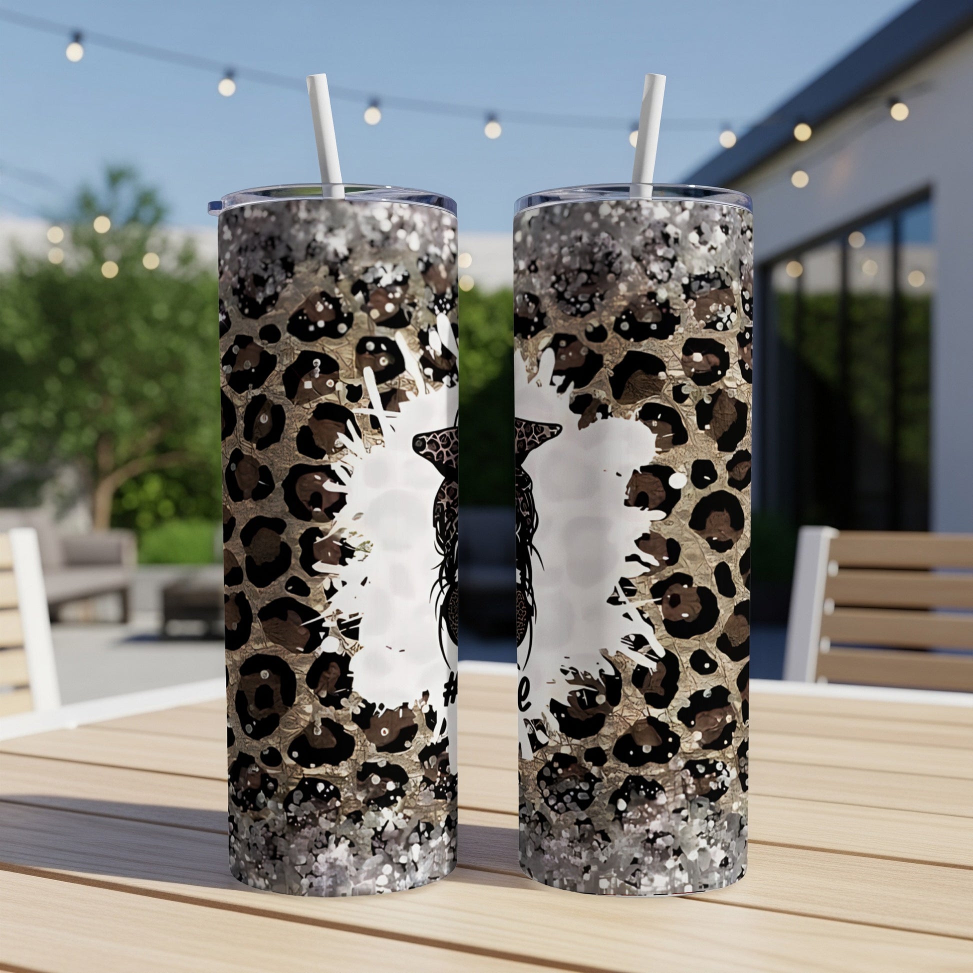 Two tumblers with leopard print and glitter designs on an outdoor table.