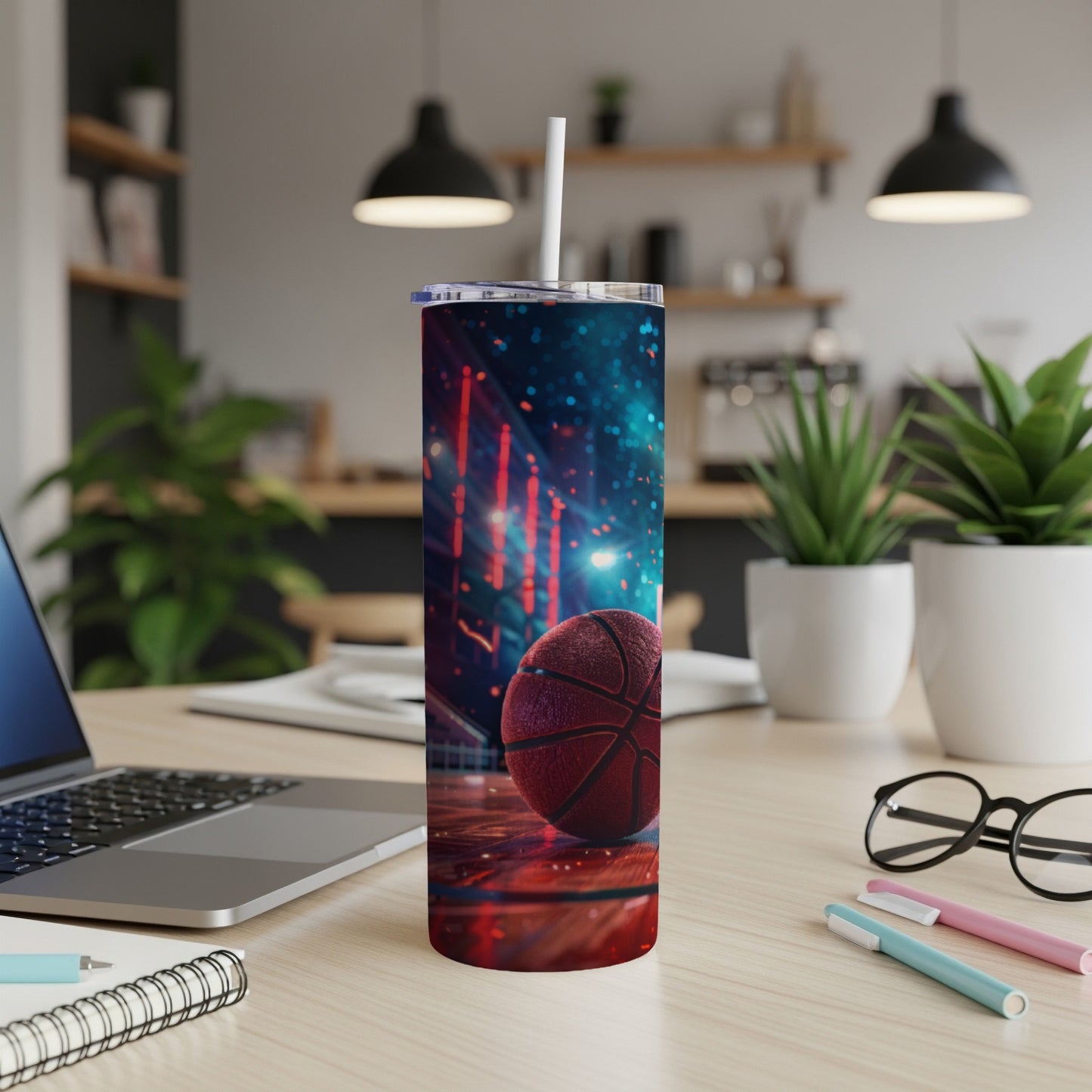 Basketball tumbler with straw on a desk with a laptop and pens.