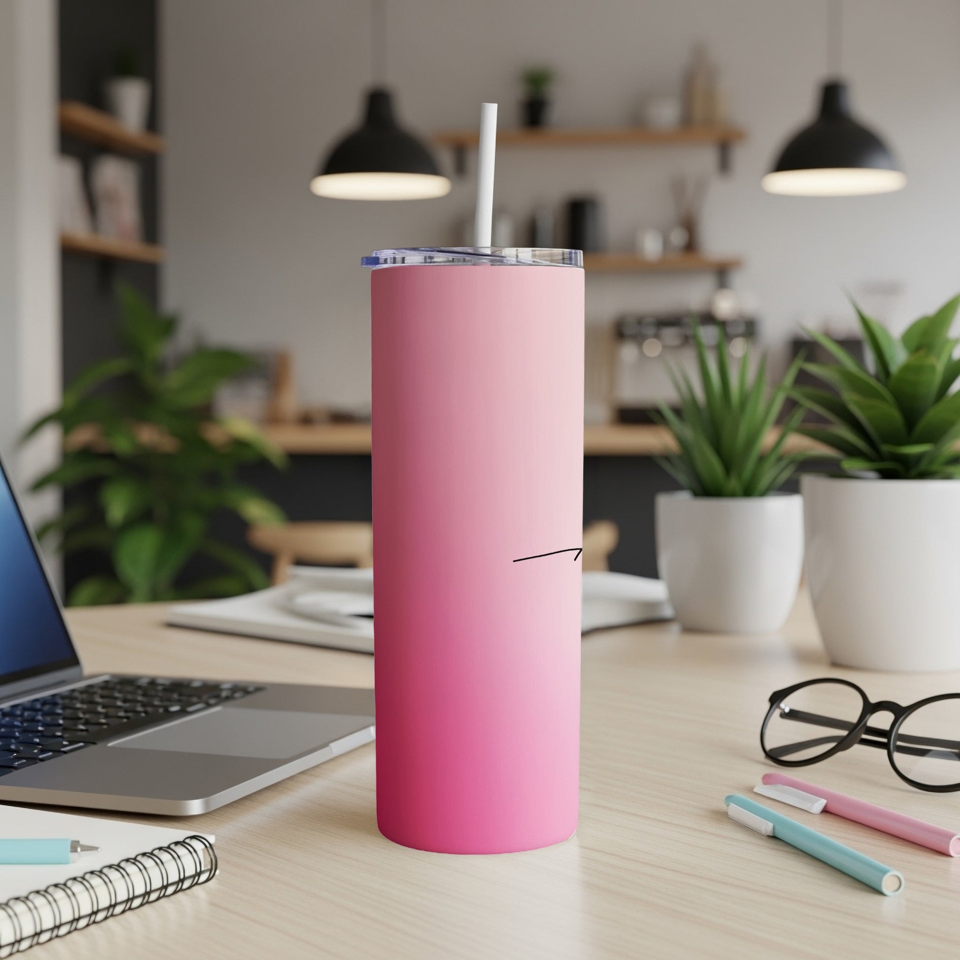 Pink gradient skinny tumbler with straw on a desk.