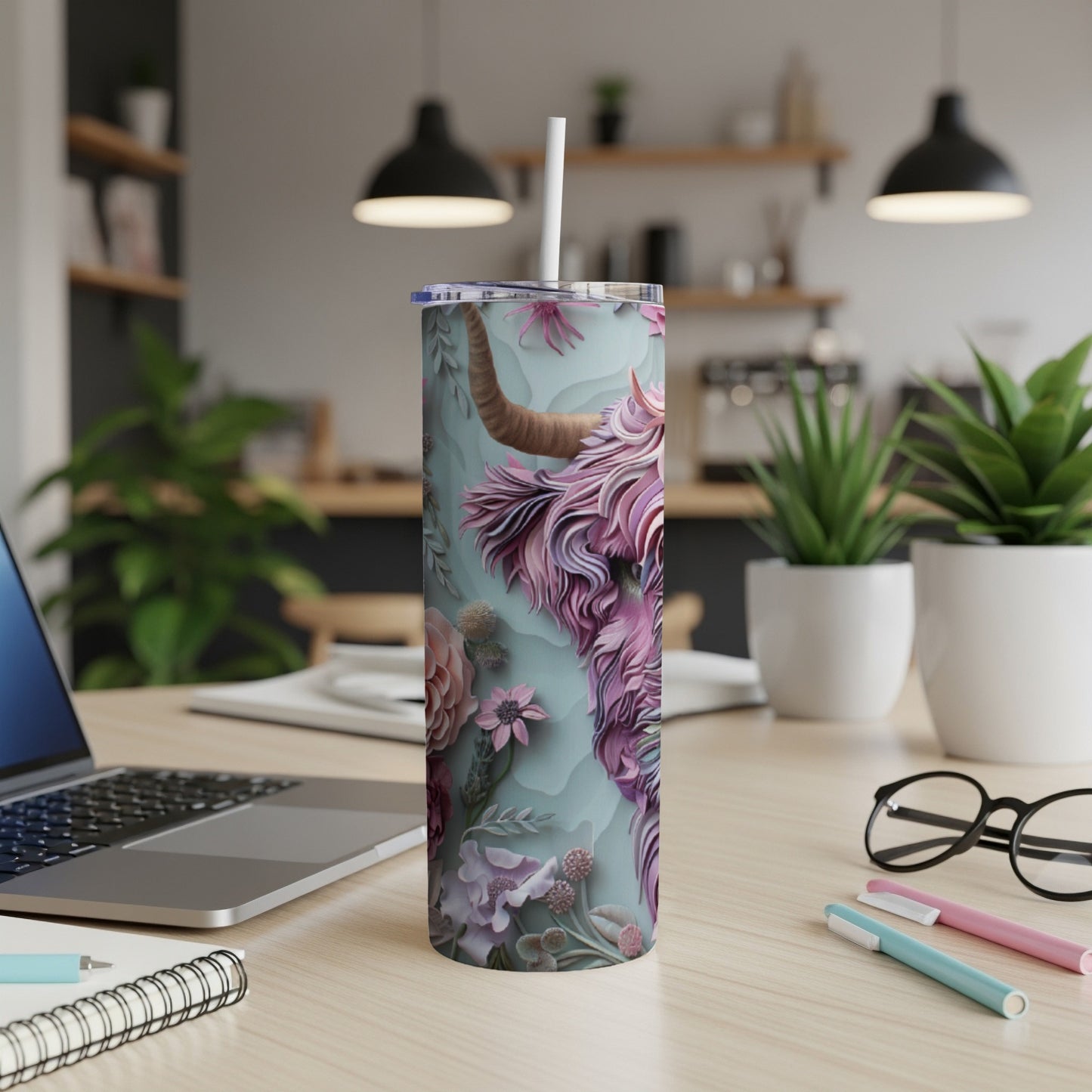 Tall tumbler with a Highland cow and floral design, on a desk.