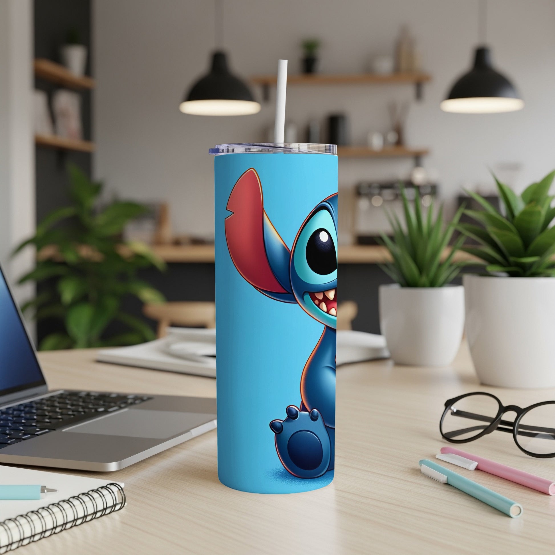 Blue Stitch tumbler with straw on desk next to laptop and pens.