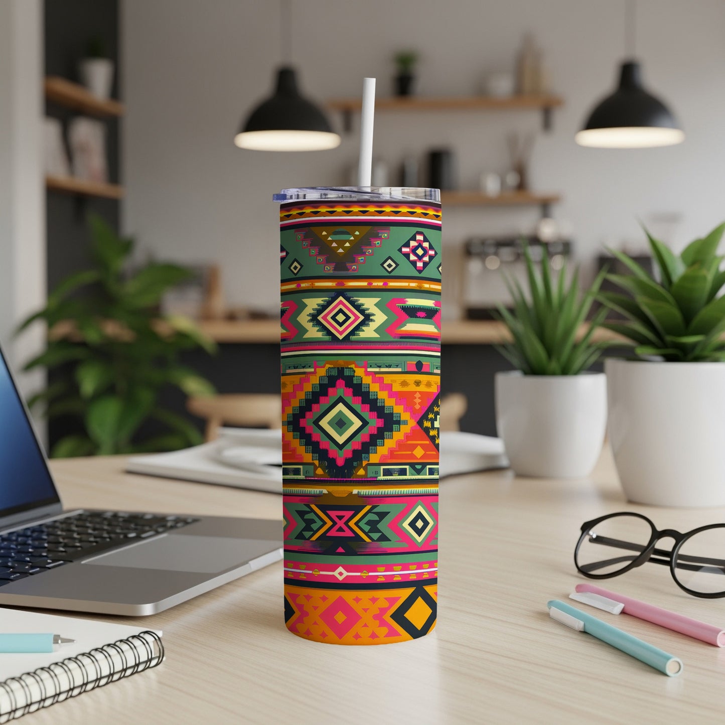 Tall, insulated tumbler with colorful geometric Southwestern pattern, straw, and laptop.