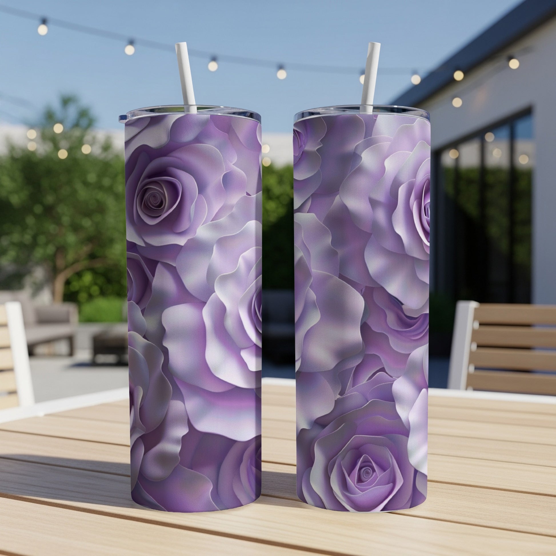 Two purple floral tumblers with straws on a wooden table outdoors.
