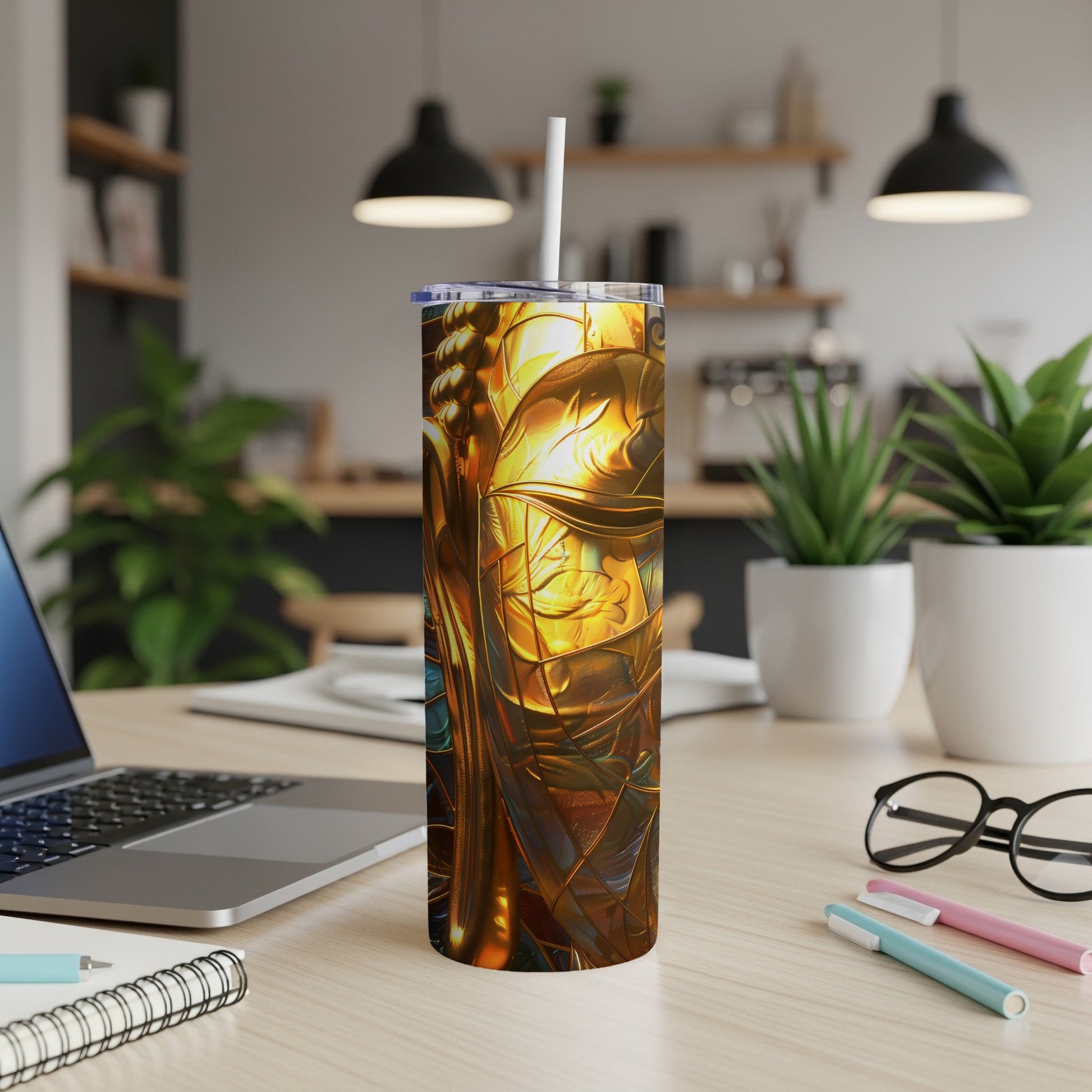 Gold and blue abstract art tumbler with straw on desk.
