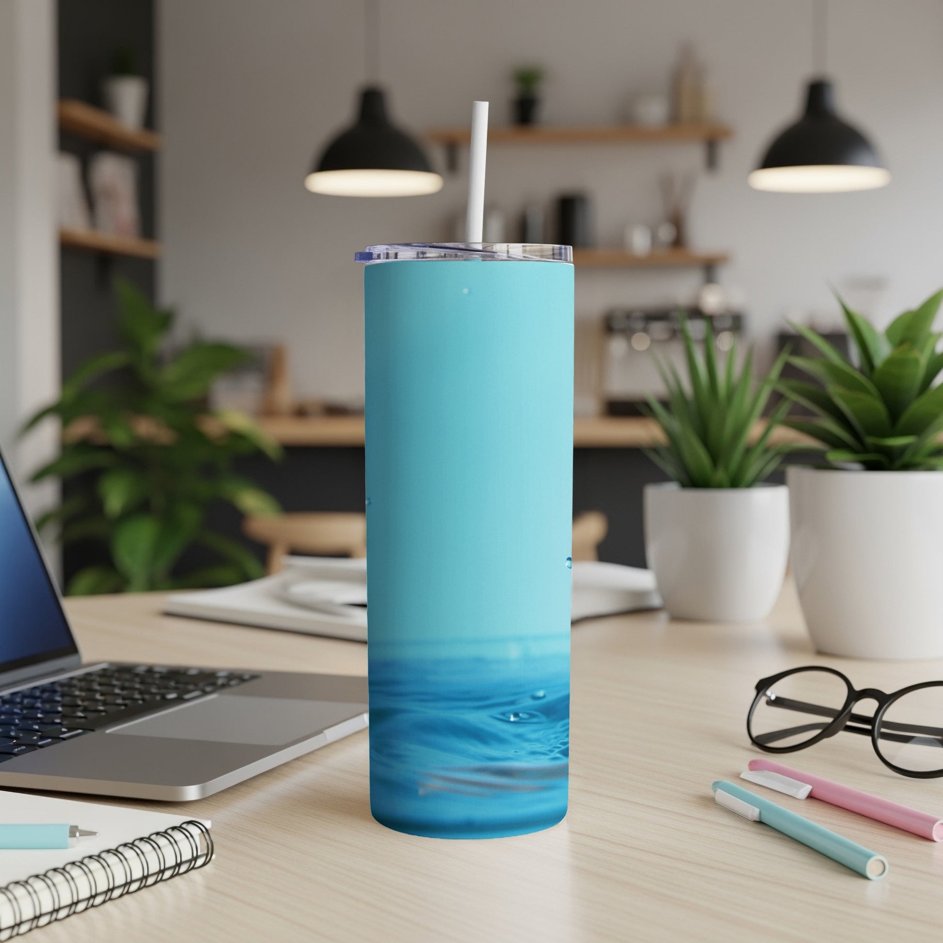 Blue tumbler with water ripple design on desk with laptop and pens.