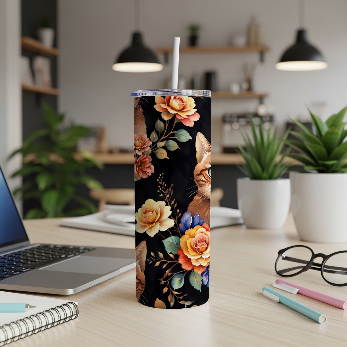 Black tumbler with floral and cat-eye design on a desk.