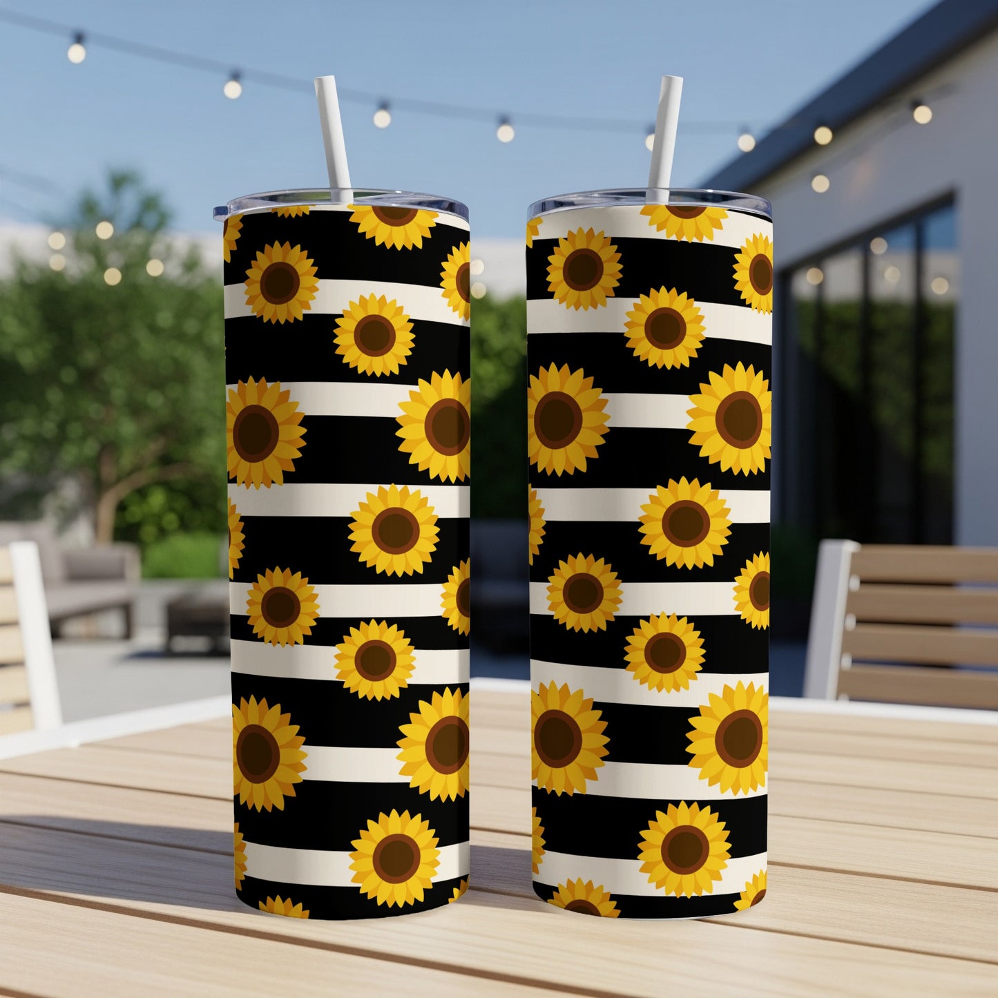 Two tumblers with black and white stripes and a sunflower pattern are displayed outdoors.