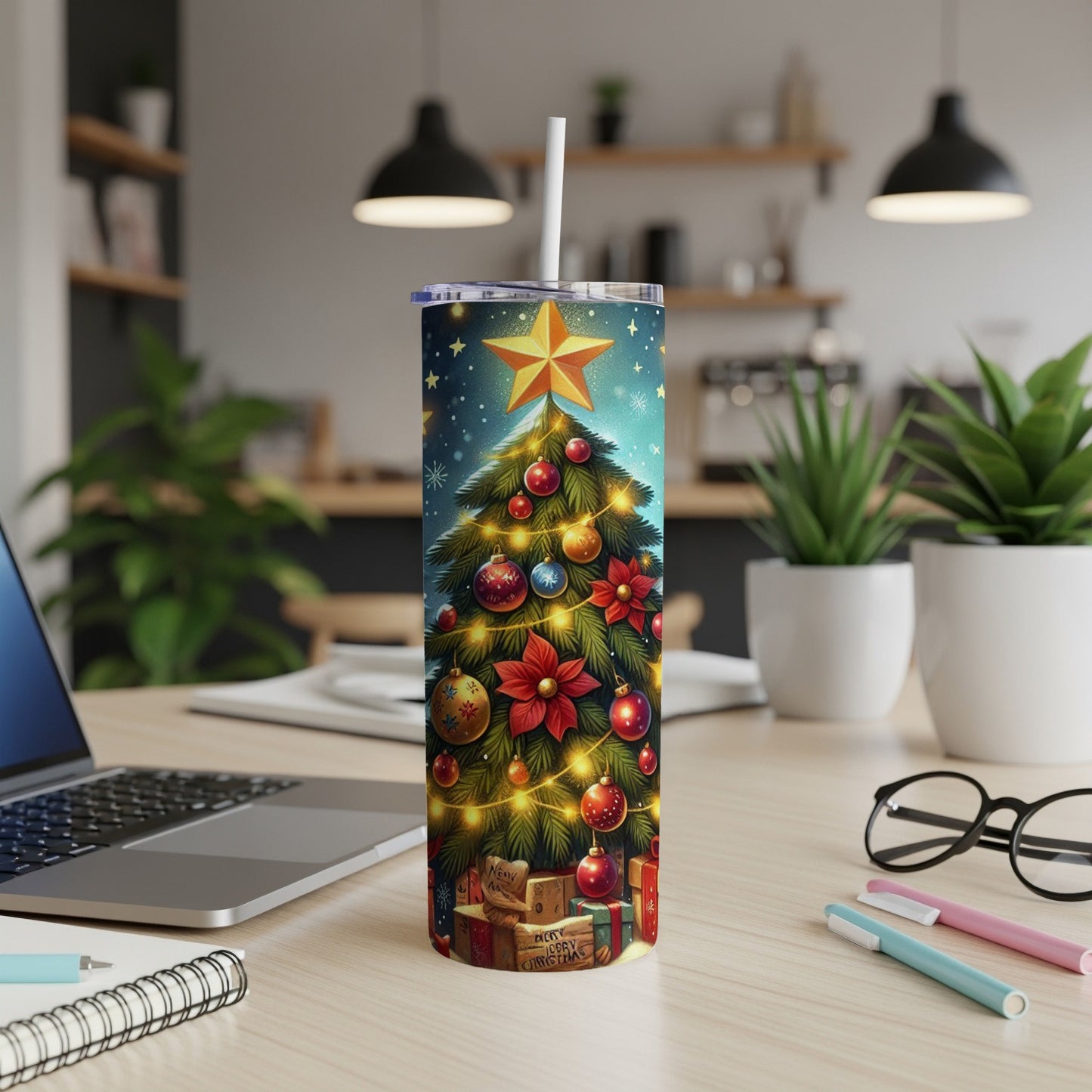 Christmas tree tumbler with presents and decorations, on a desk.