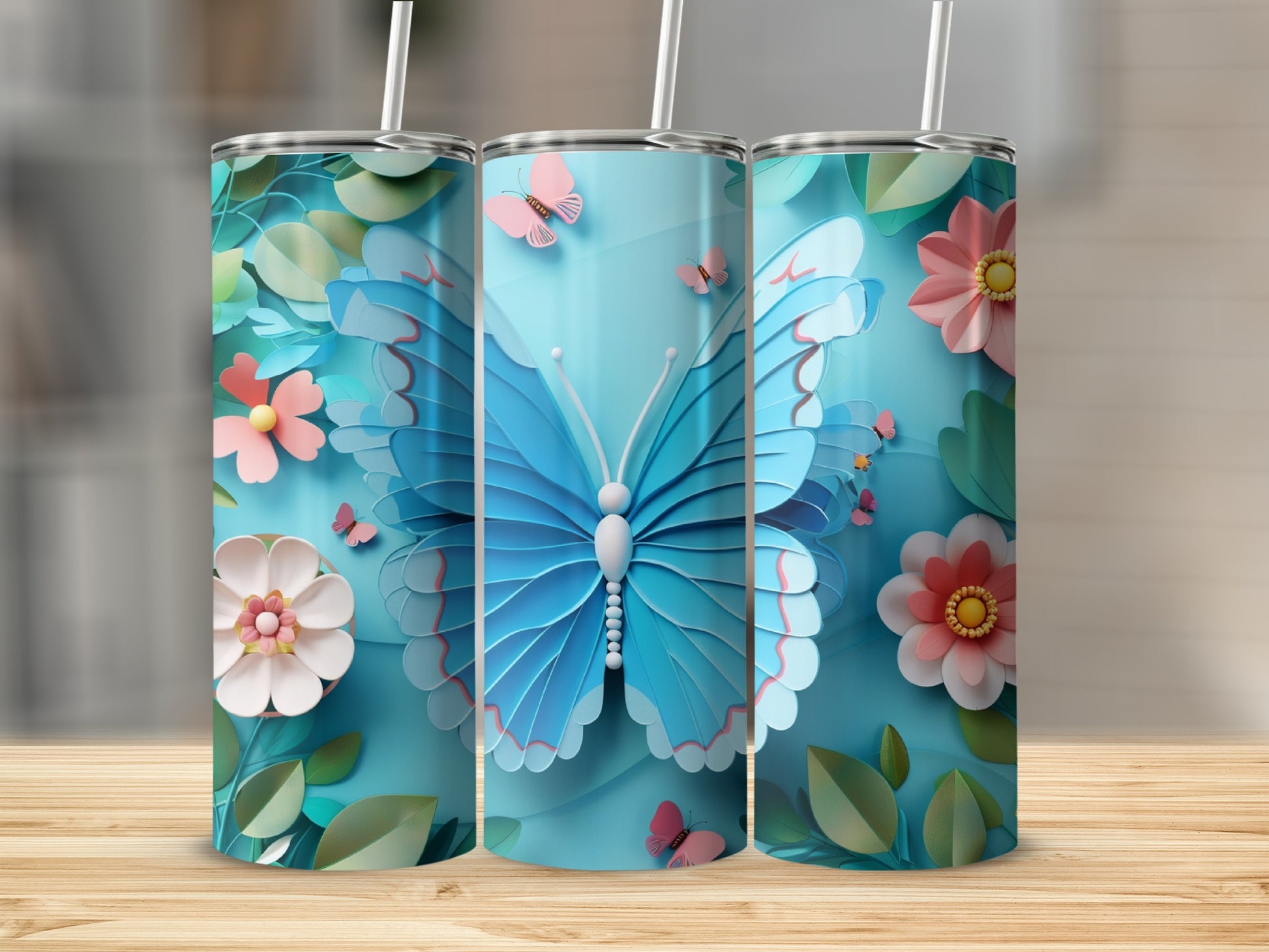Blue butterfly and floral design on three tall tumblers with straws.