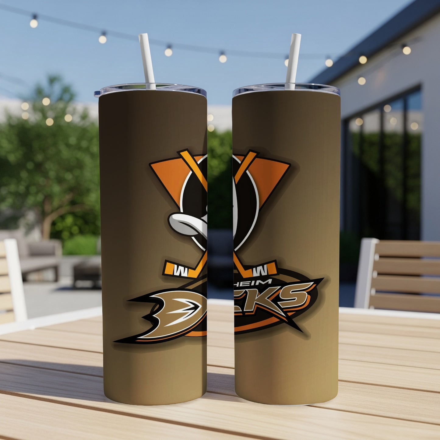 Two Anaheim Ducks tumblers with straws on a wooden table outdoors.