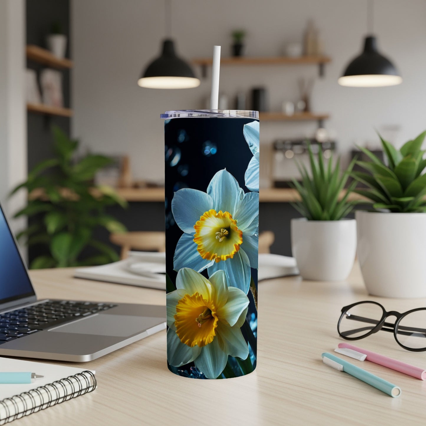 White and yellow daffodils on a blue speckled tumbler with a straw.
