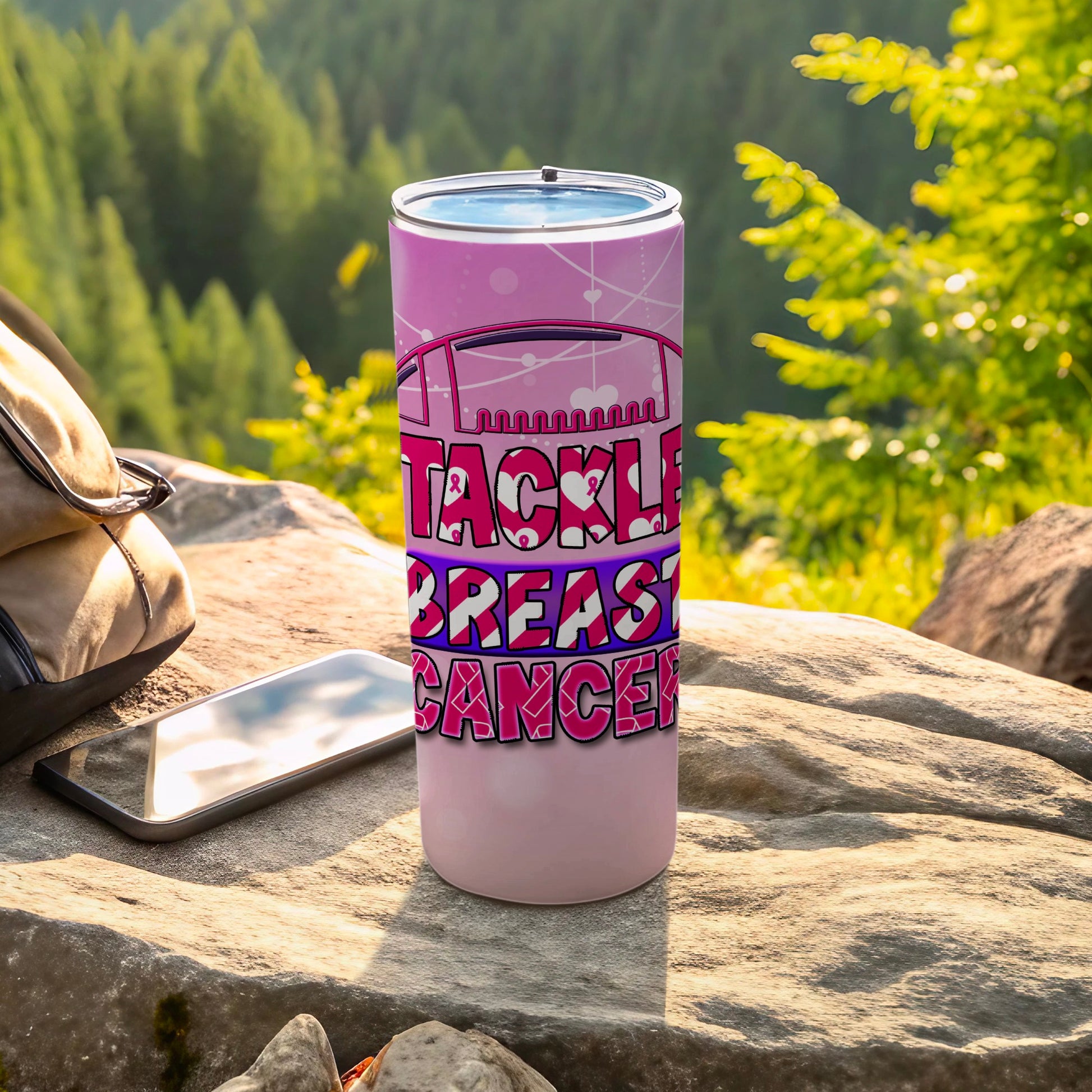 Pink tumbler with "Tackle Breast Cancer" text, placed on rocks.