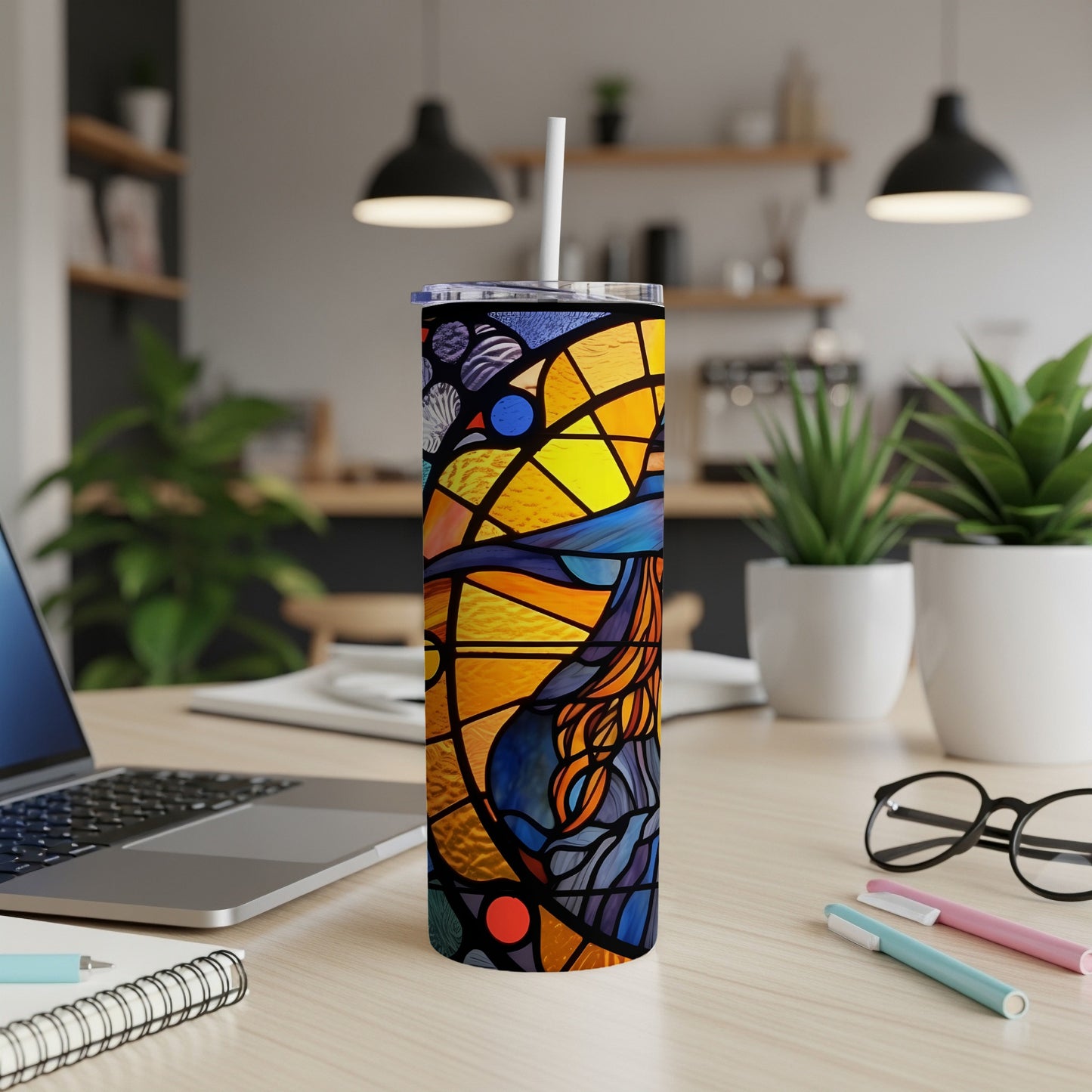Stained glass design tumbler with a straw on a desk.