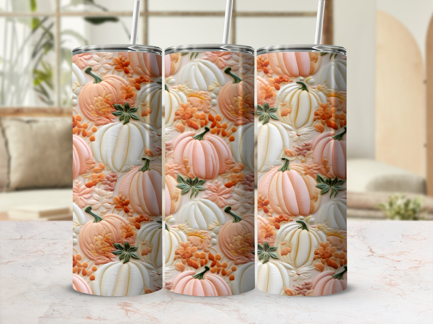 Three tumblers with a pumpkin and leaf pattern on a marble surface.