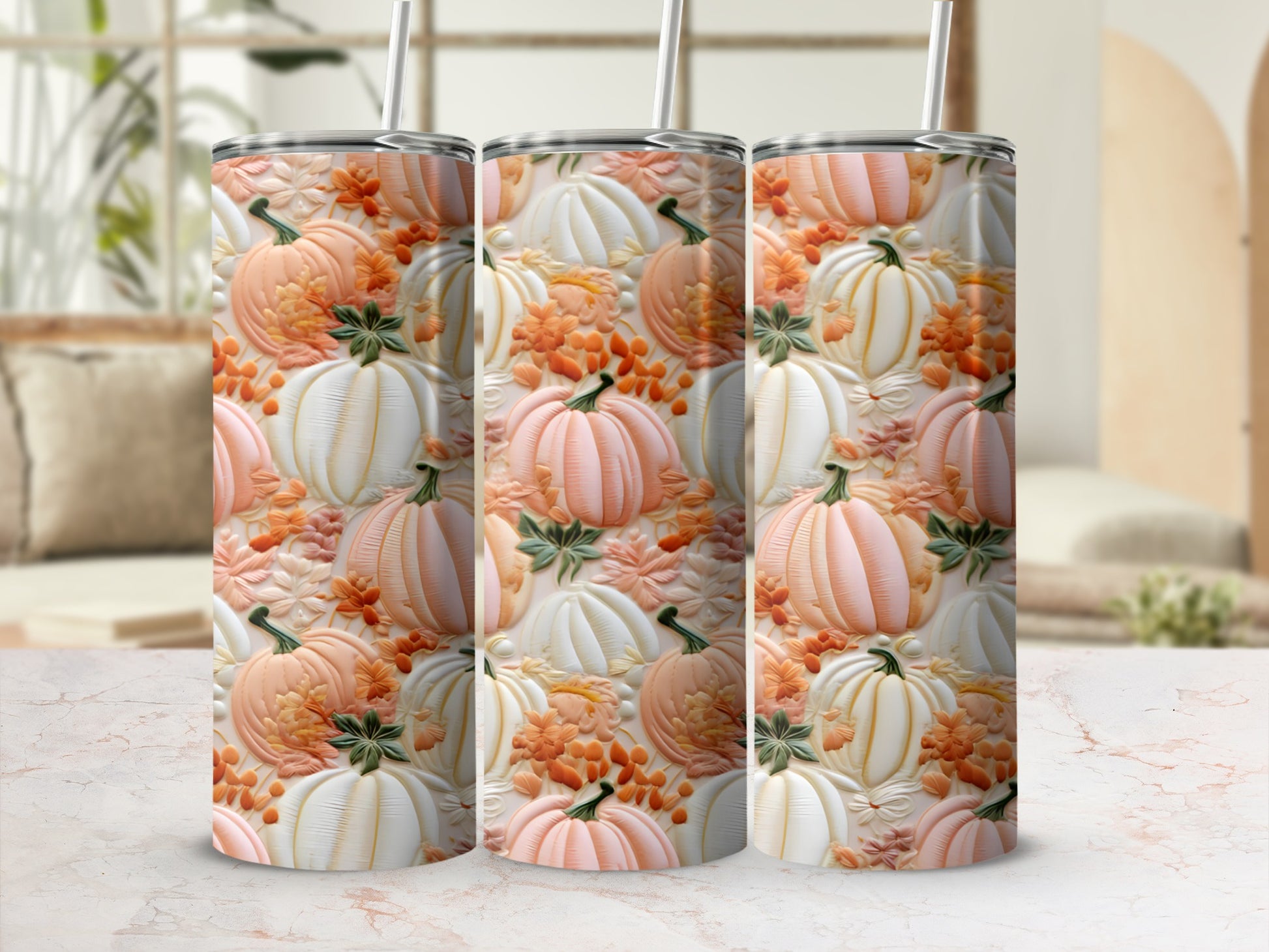 Three tumblers with a pumpkin and leaf pattern on a marble surface.
