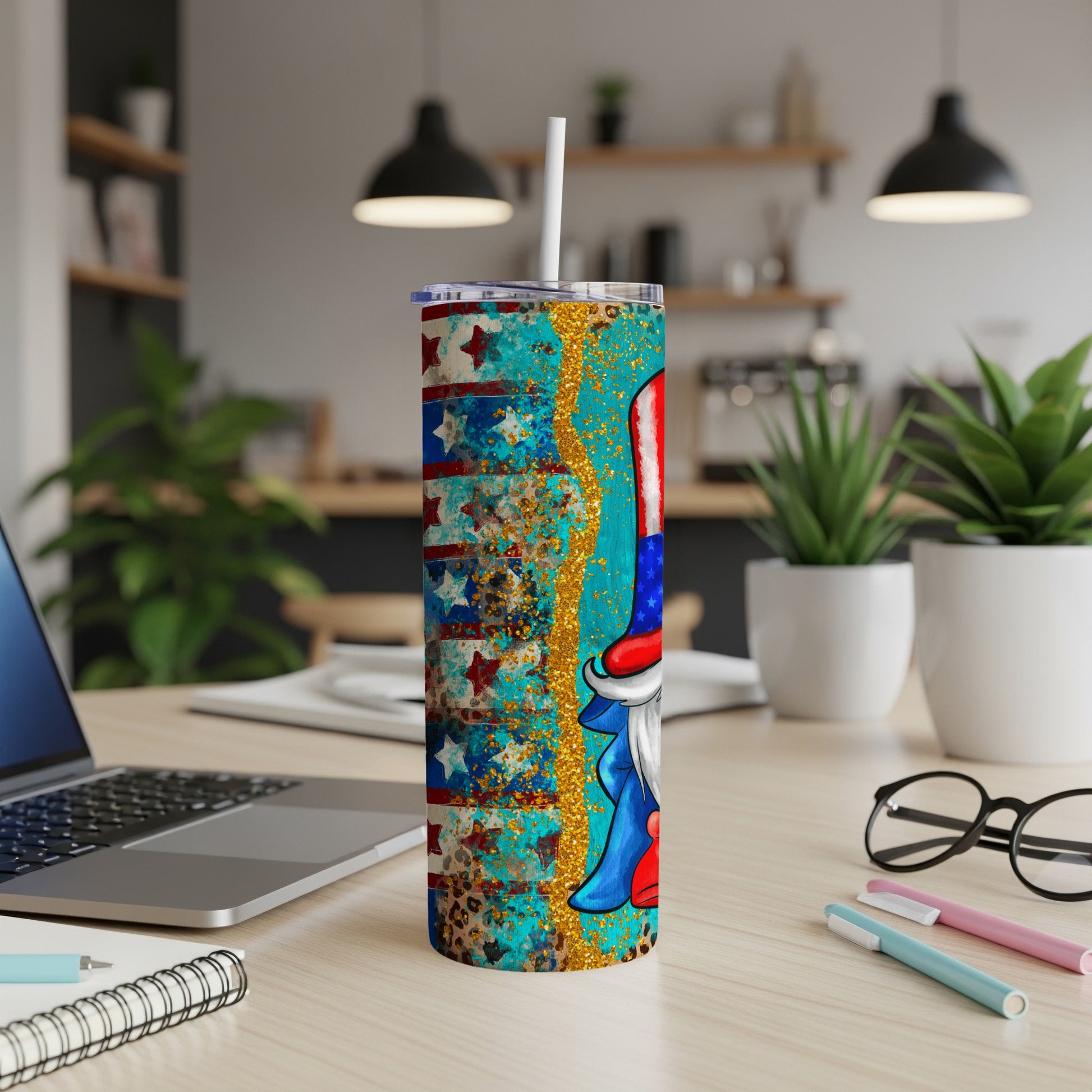 Patriotic gnome tumbler with stars, stripes, and glitter on a desk.