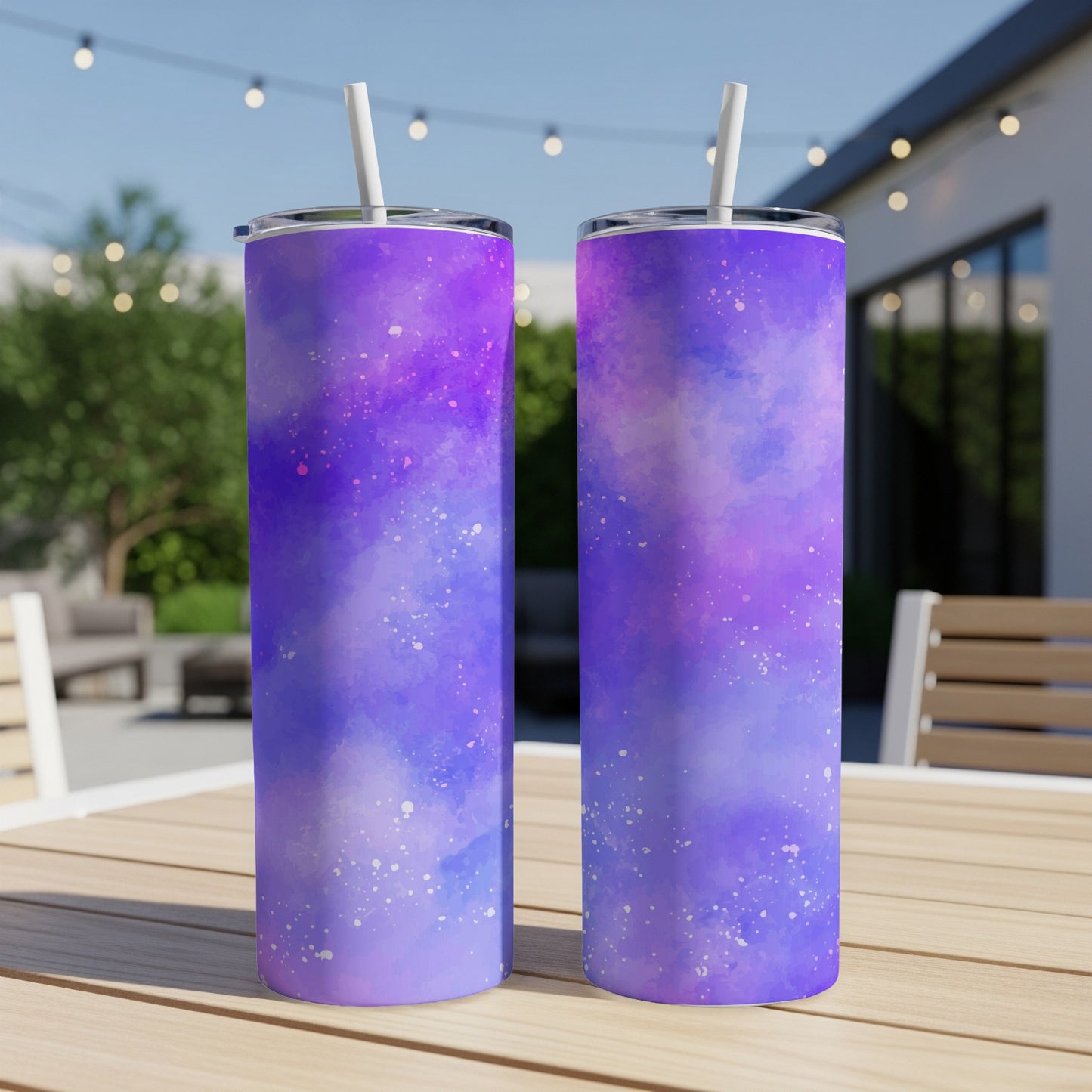 Two purple galaxy pattern tumblers with white straws sit on a wooden table.