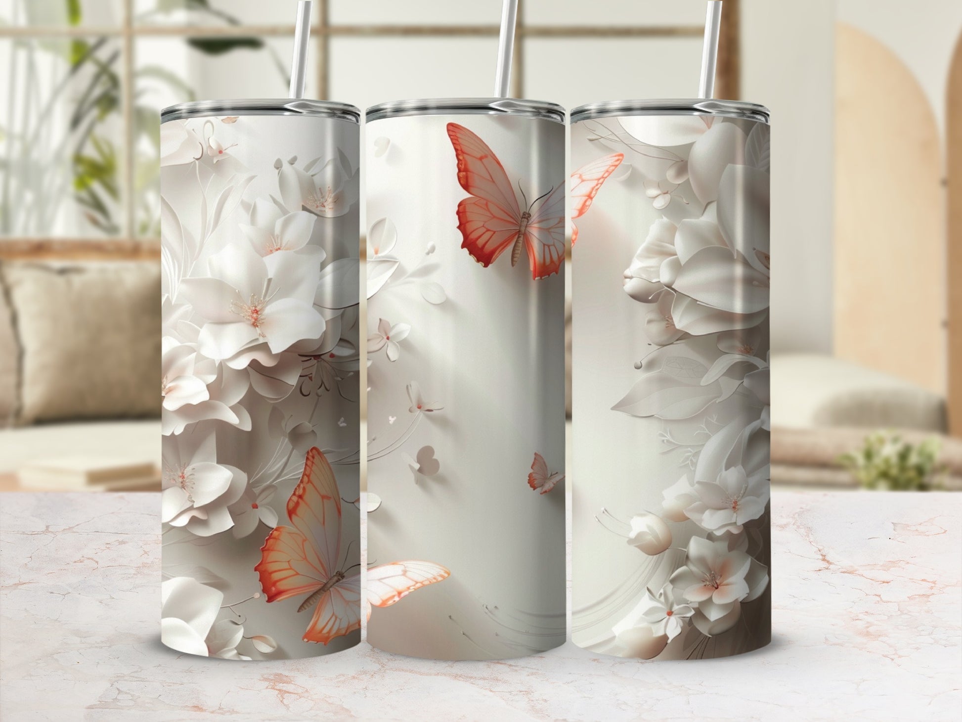 Three tumblers with floral and butterfly designs on a marbled surface.