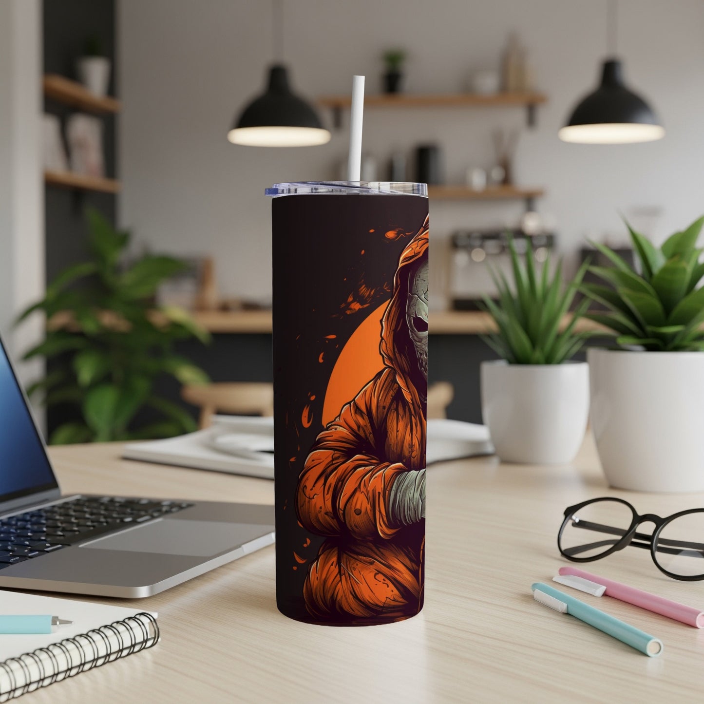 Tumbler with grim reaper graphic in orange and black, on a desk.