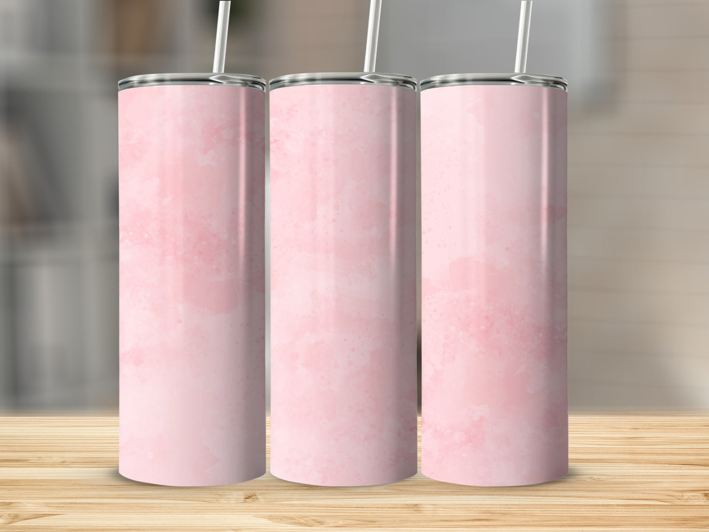 Three pink watercolor tumblers with straws on a wooden surface.