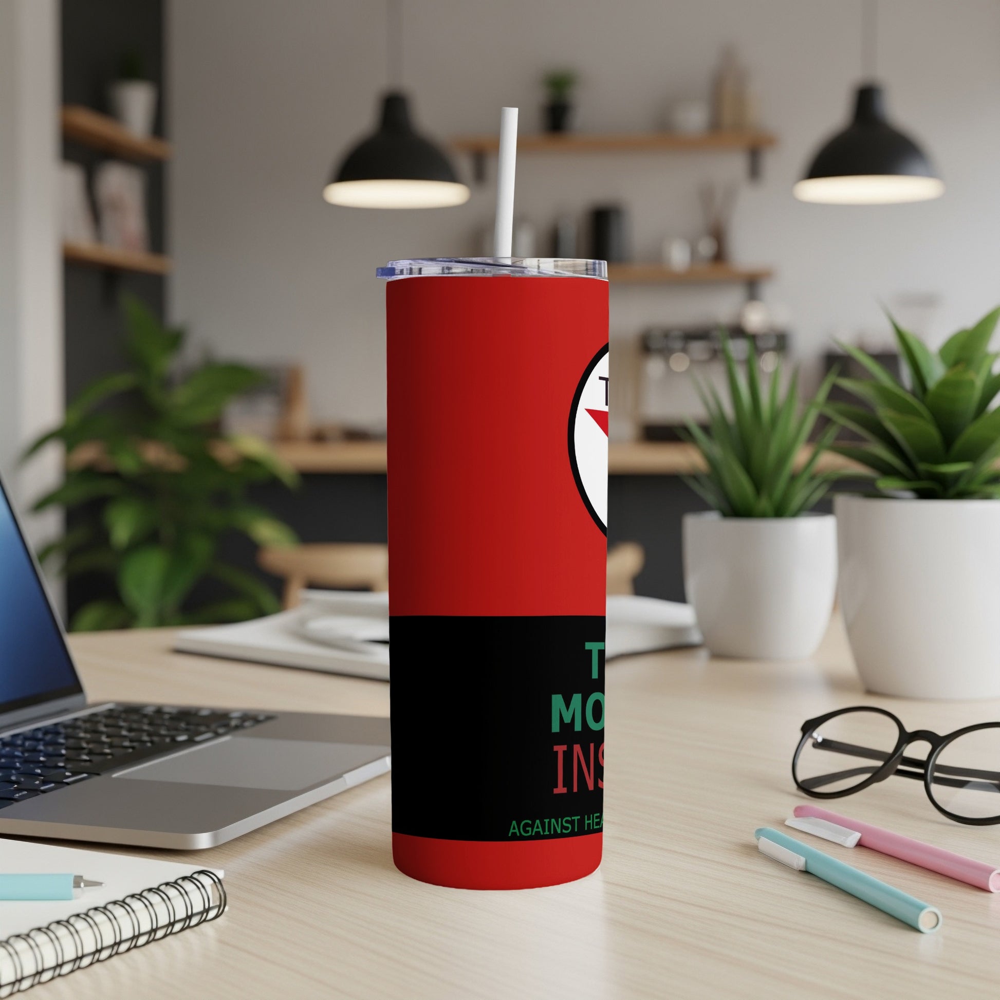 Red tumbler with white straw, black stripe, and green text that reads "AGAINST HER".