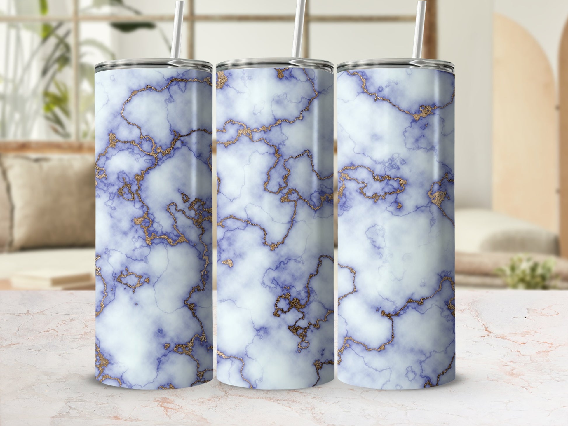 Three white marble tumblers with gold veining and a straw.