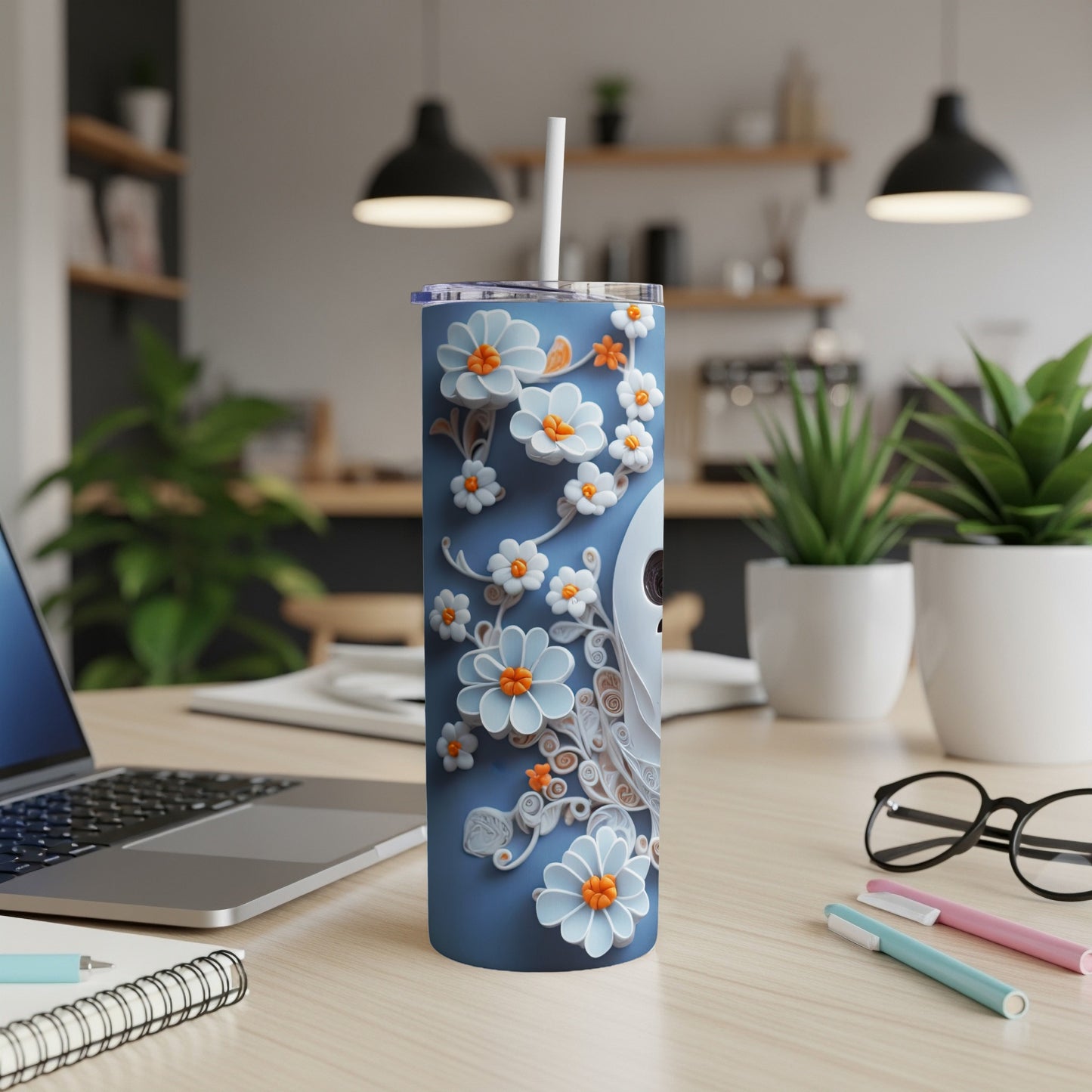 Blue tumbler with white and orange floral relief design and white straw.