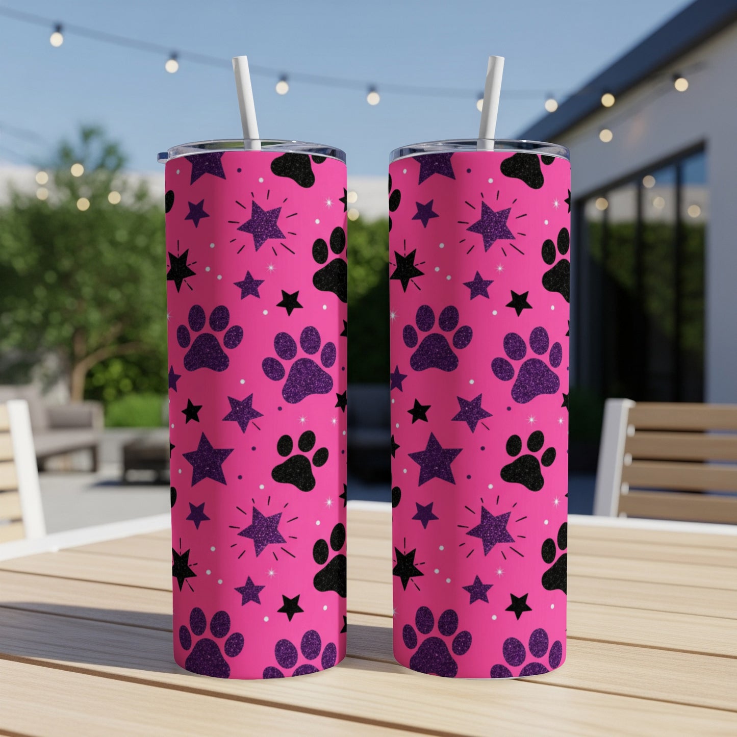 Pink tumbler with paw prints and stars, on a table outdoors.