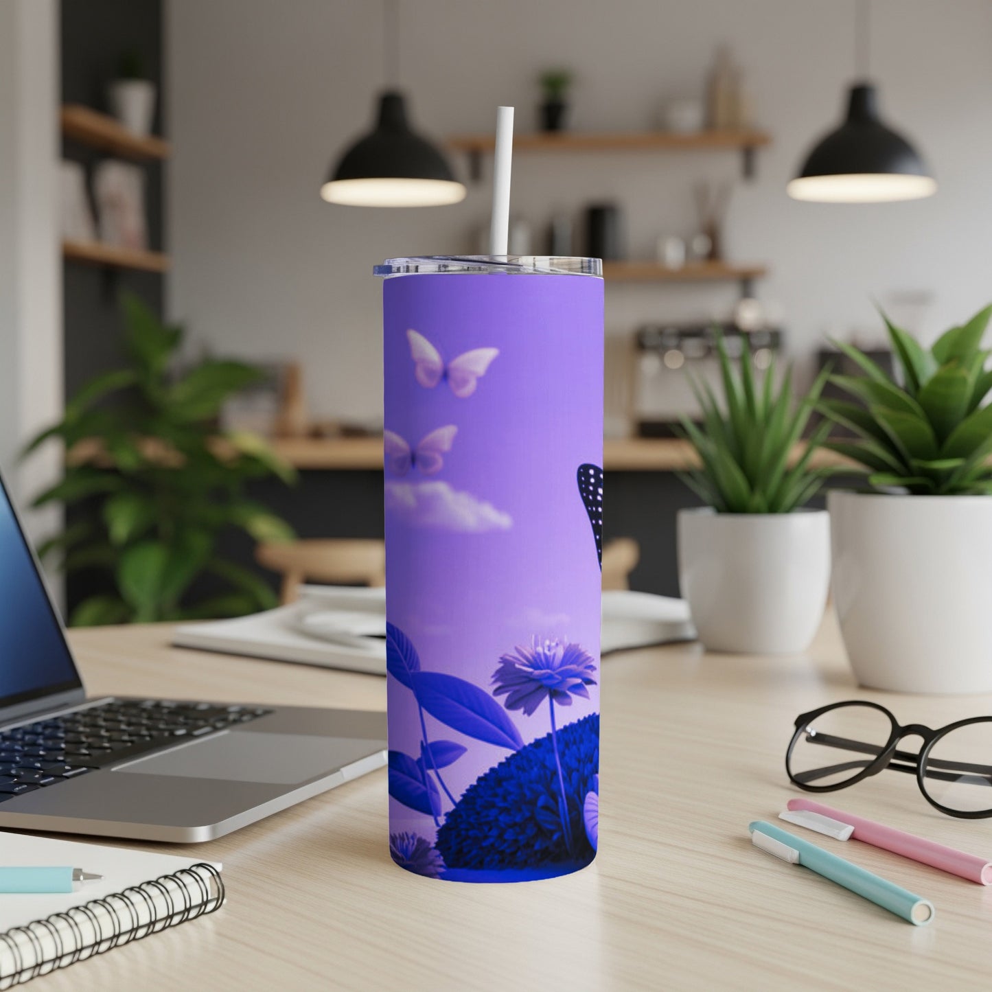 Purple tumbler with butterflies and blue flowers on a desk.