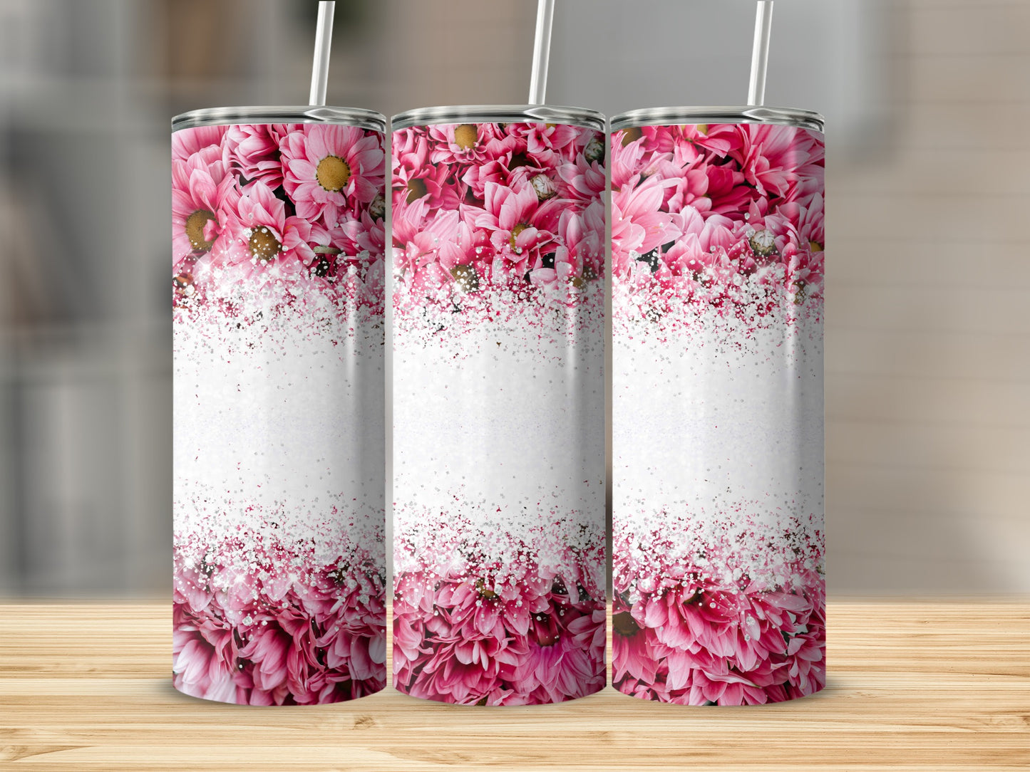 Three pink floral tumblers with white glitter overlay sit on a wooden surface.