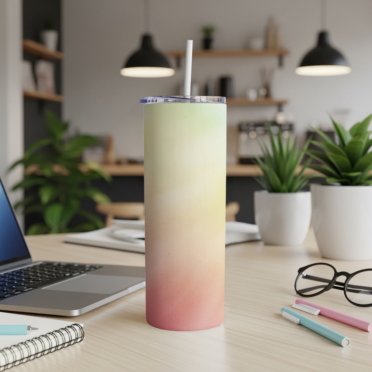 Gradient pink, yellow, and green tumbler with straw on desk.