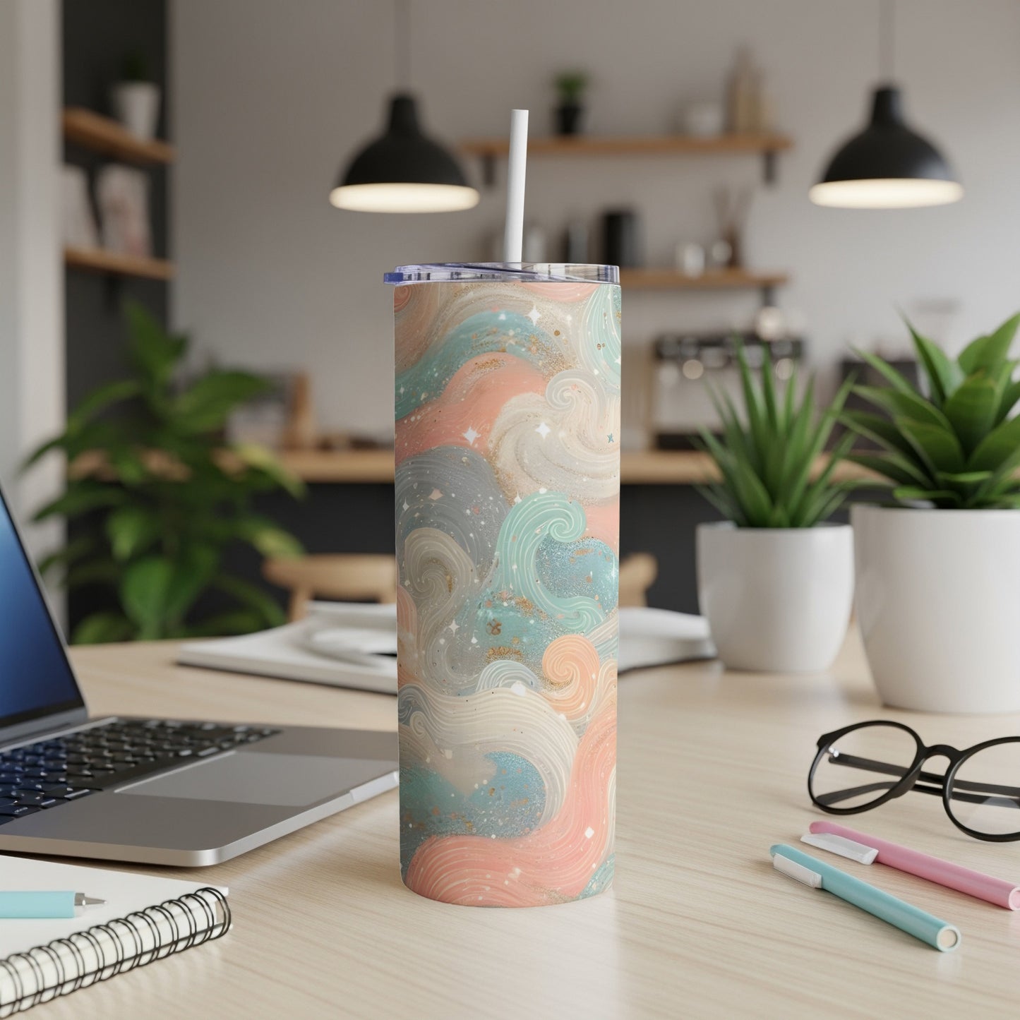 Tall tumbler with pastel swirls and glitter patterns, on a desk.